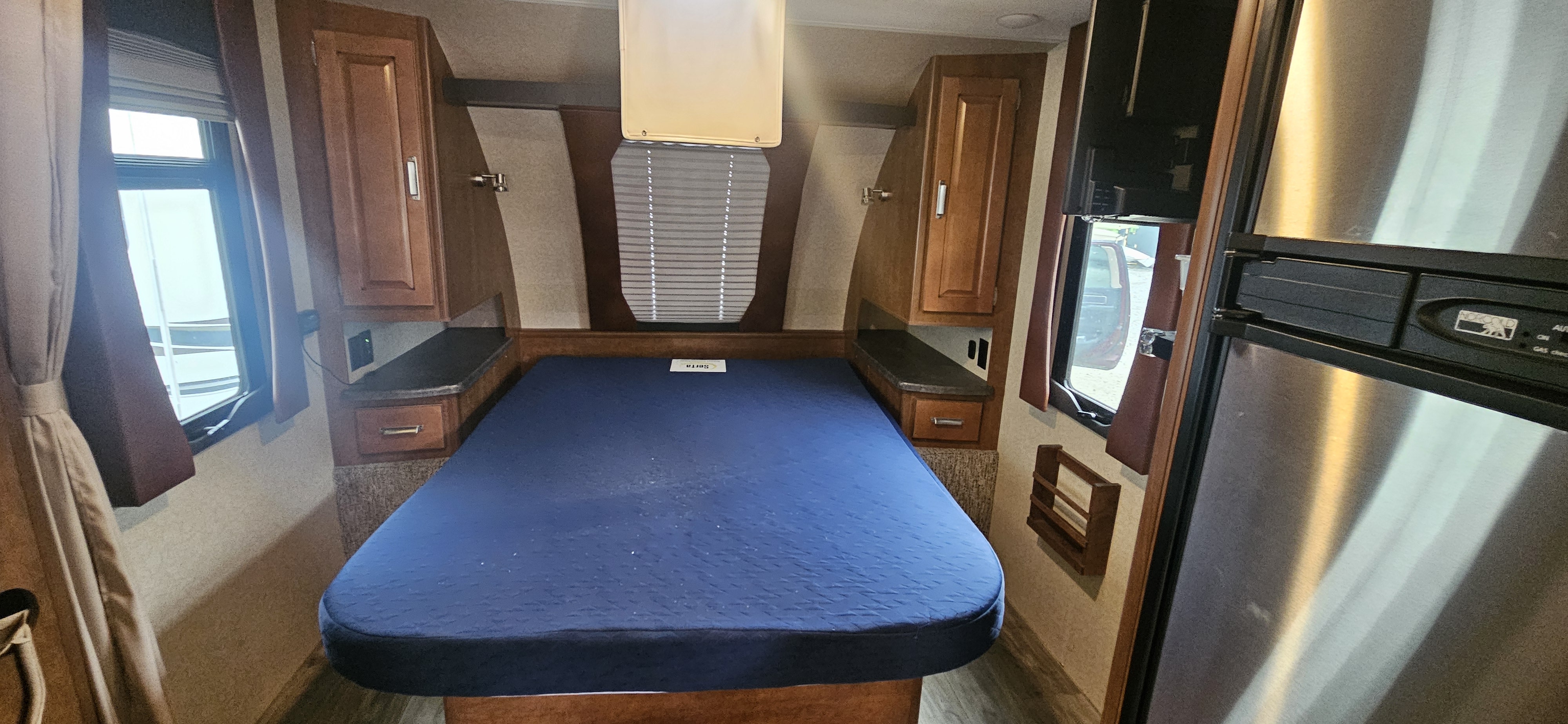 RV rental bedroom features a blue bed, built-in cabinets, windows, and side storage for a comfortable journey.. Lance 1995 2018