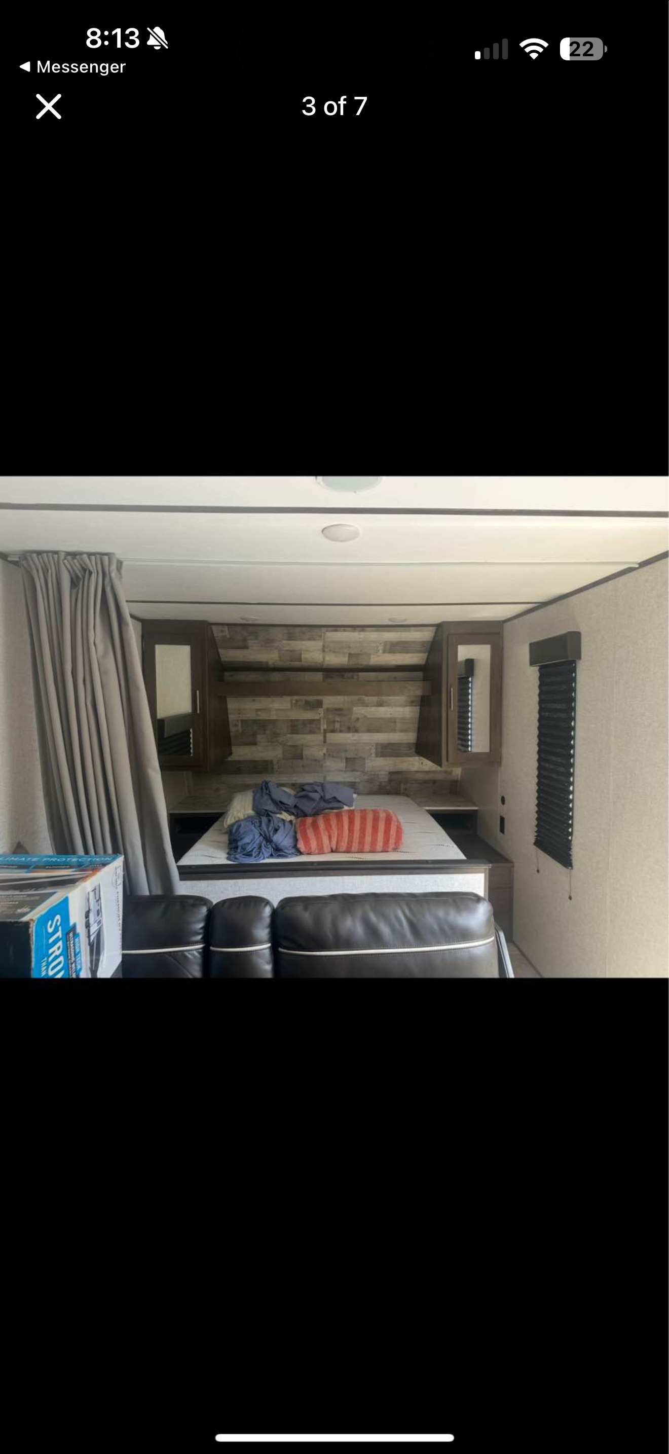 Inside an RV rental, a bedroom features a bed with bedding, storage cabinets, privacy curtains, and a window with blinds.. Dutchmen Coleman Lantern LT 2024