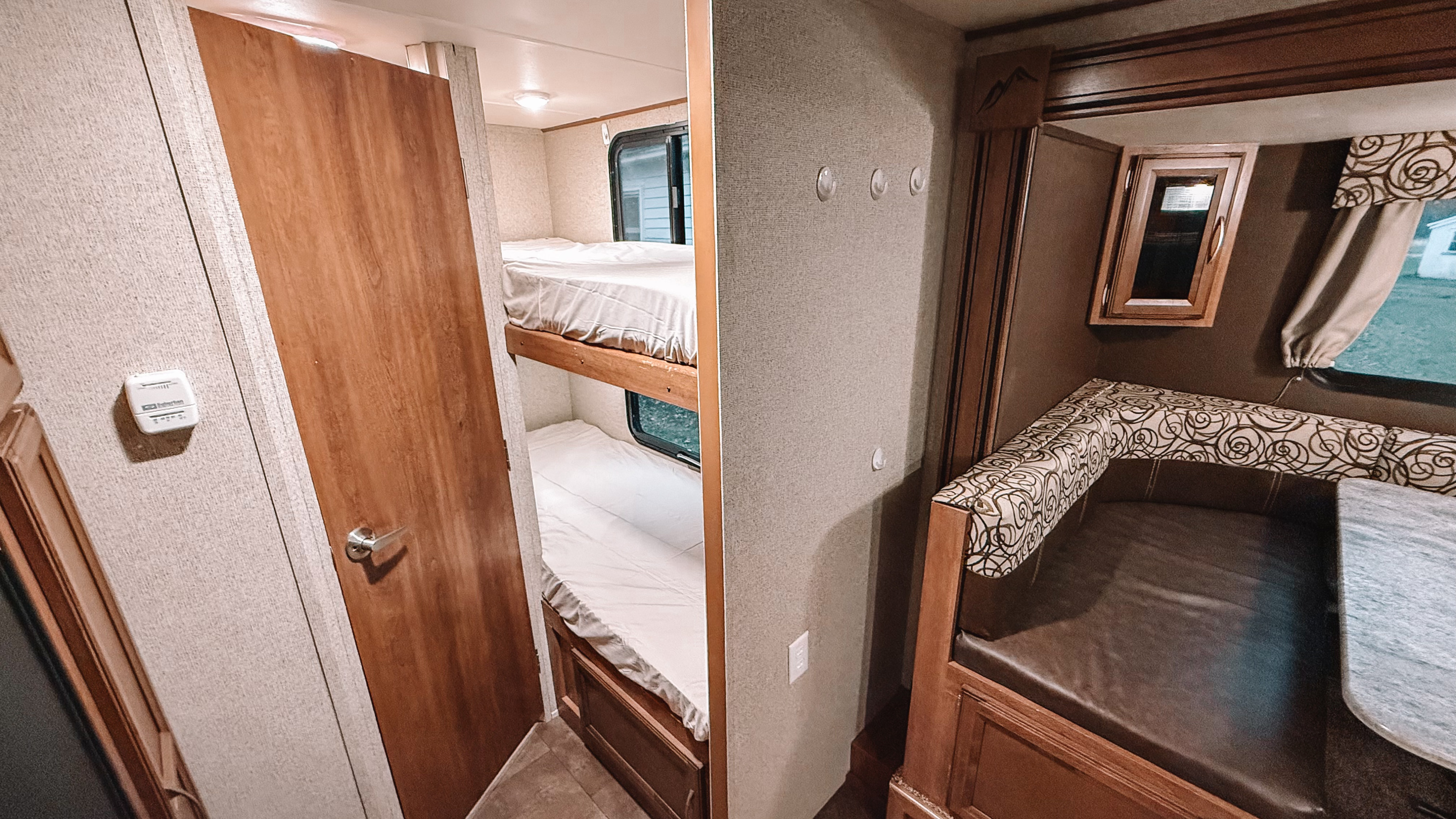 Cozy RV rental interior: bunk beds, a dinette with patterned cushions, and a thermostat. Great for trips!. Coachmen Apex 2016