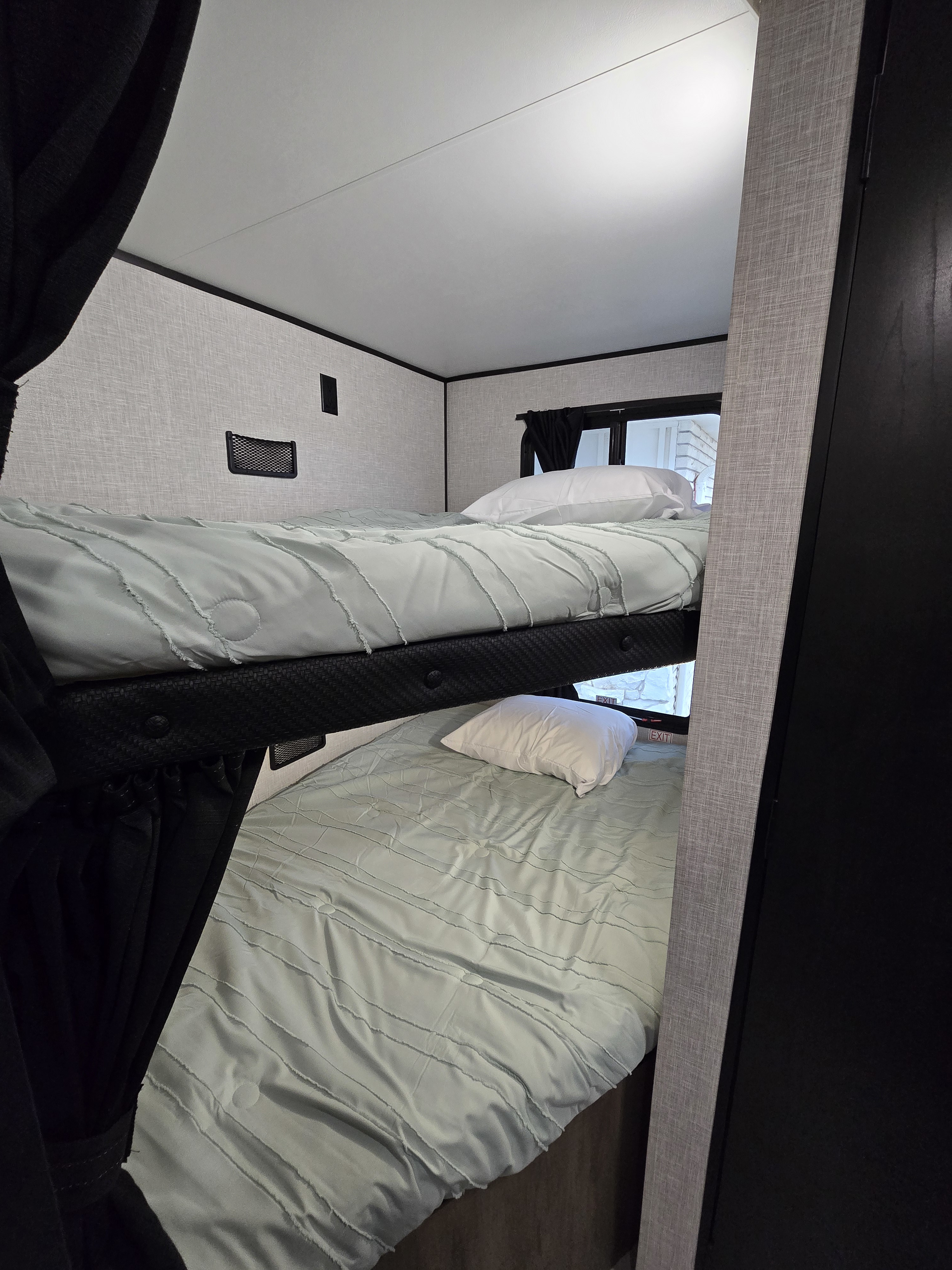 Cozy RV rental bunk beds: two beds with light blue comforters and white pillows, set in a compact, modern interior.. Starcraft RV 26BH 2025