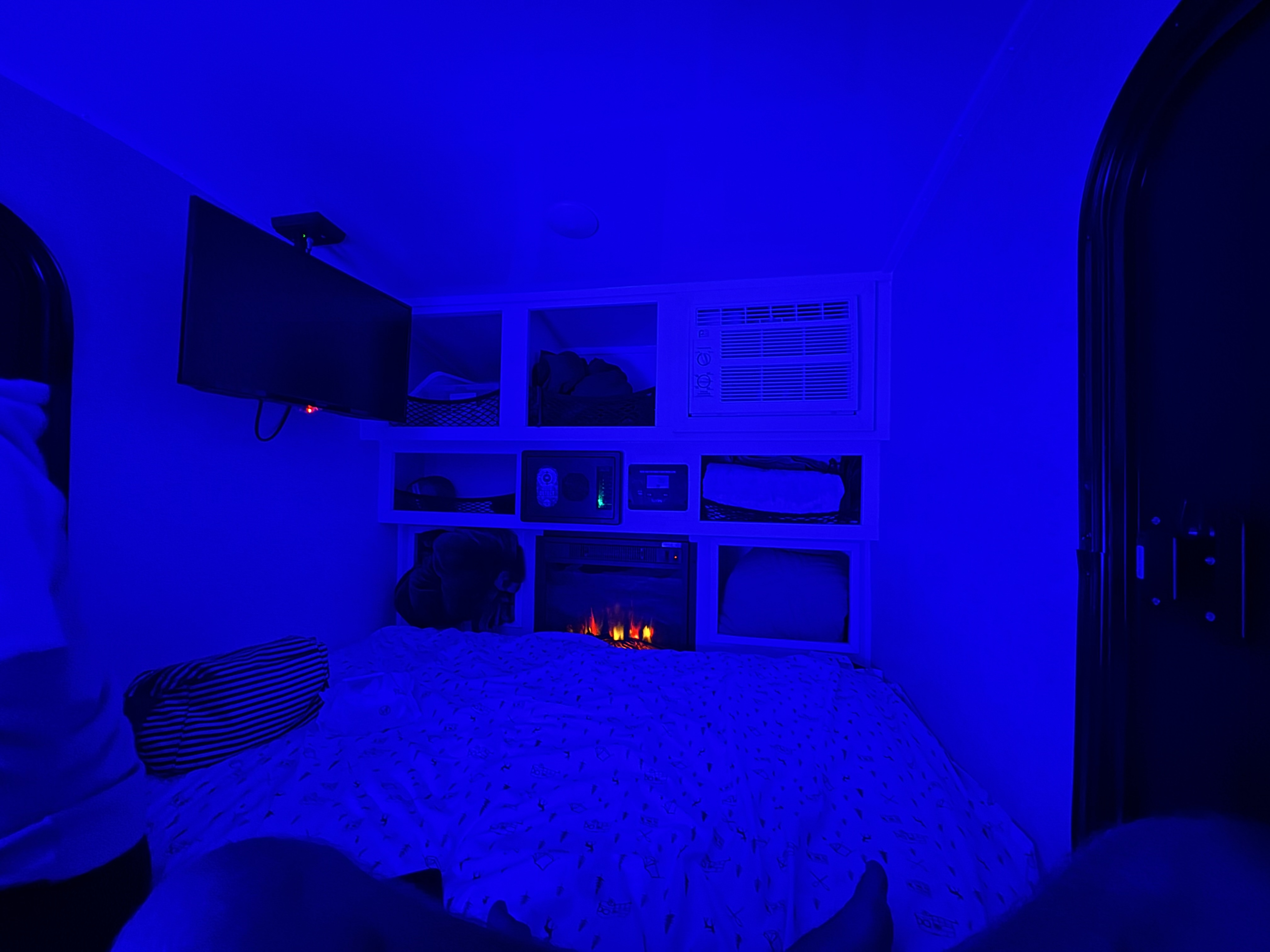 Cozy blue-lit RV rental interior with bed, TV, AC, and electric fireplace. Enjoy relaxing amenities in this compact space.. Modern Buggy 12 LRK 2026