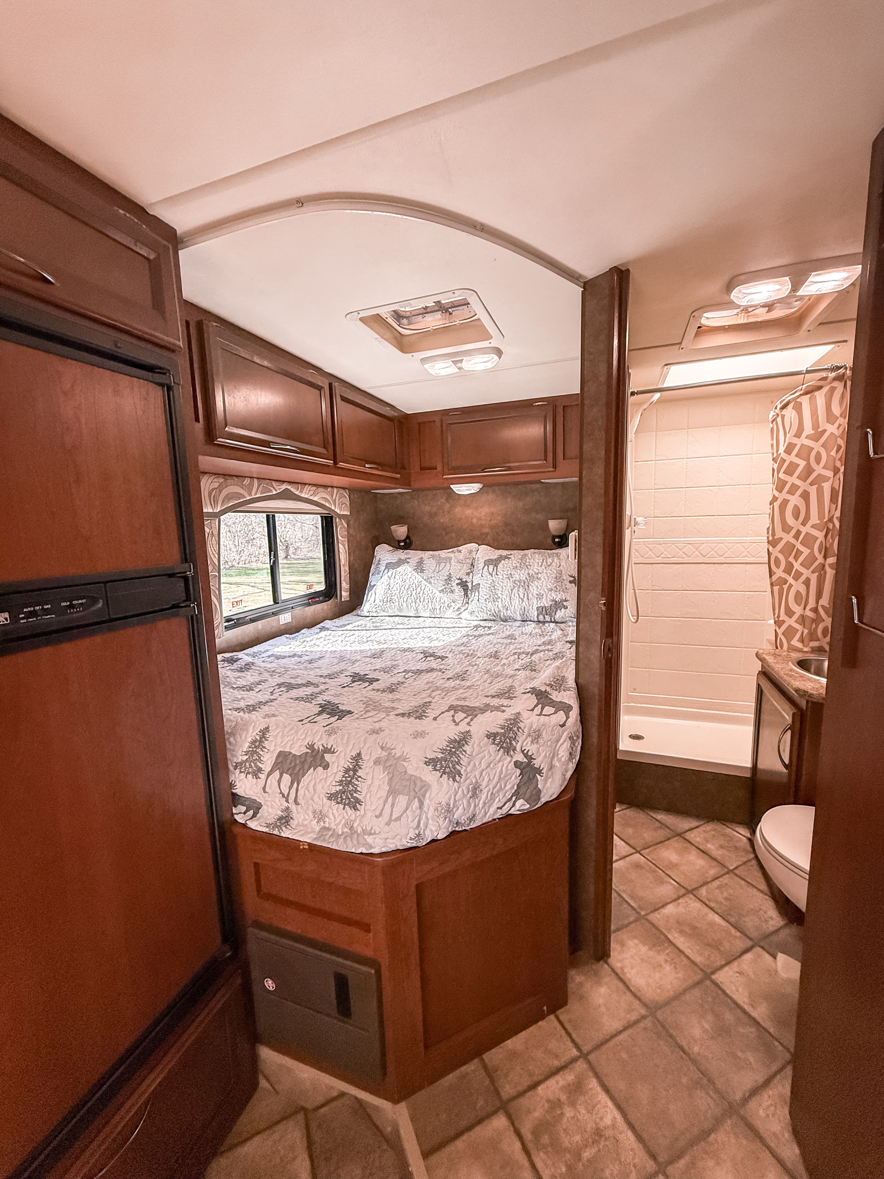 Explore this RV rental's cozy bedroom with moose bedding, a fridge, and a compact bathroom with a shower and toilet.. Thor Motor Coach Chateau 2013