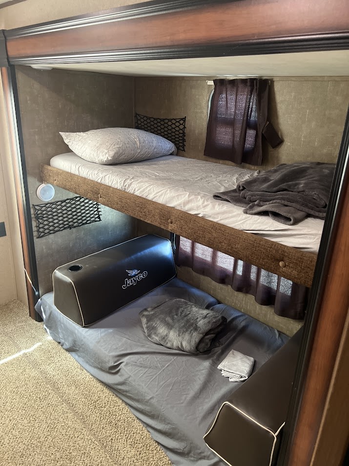 Cozy RV rental bunk beds: top with pillow, lower sleeping area with Jayco cushions. Storage nets & privacy curtains.. Jay Flight 32BHDS 2016