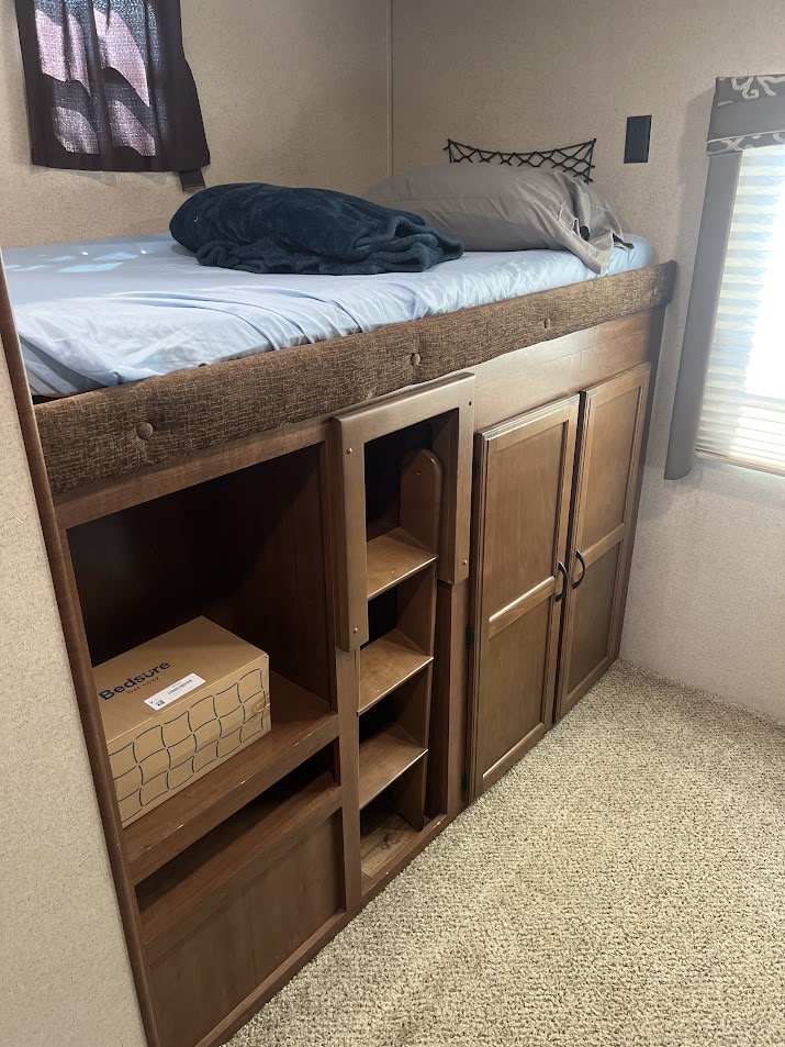 RV rental bunk bed with built-in wooden storage cabinets & ladder. Light blue bedding in a cozy camper interior.. Jay Flight 32BHDS 2016