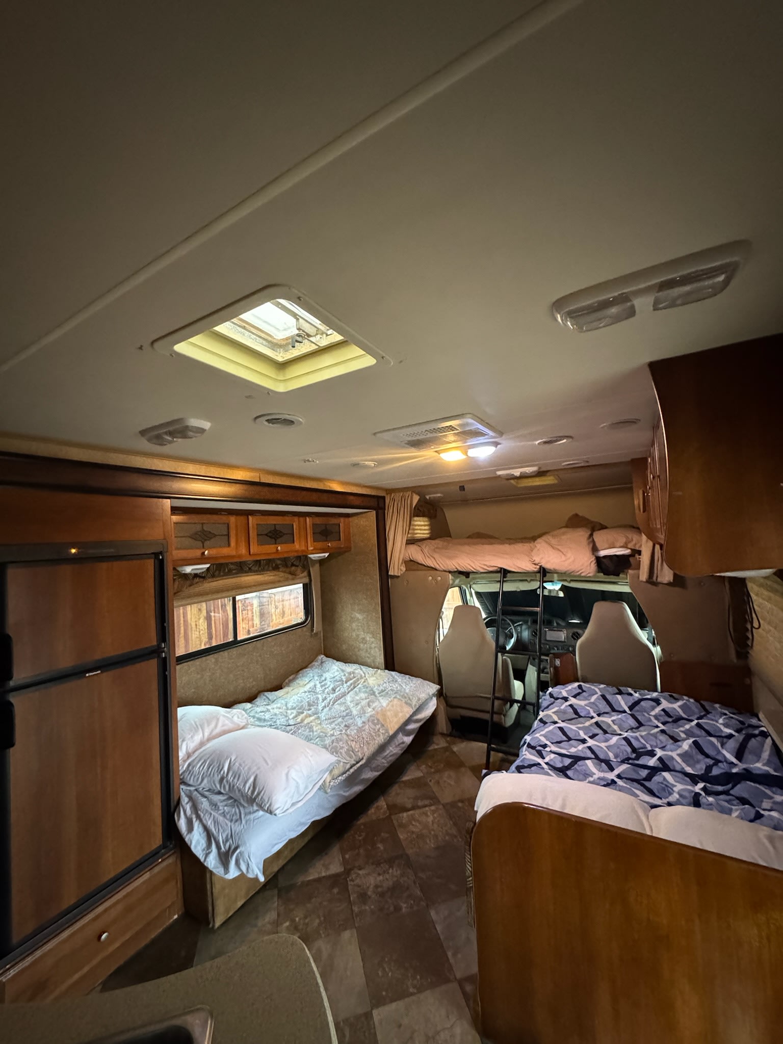 Explore this rv rental's interior, featuring three distinct sleeping areas, a refrigerator, and a skylight overhead.. Forest River Coachmen Leprechaun 2015