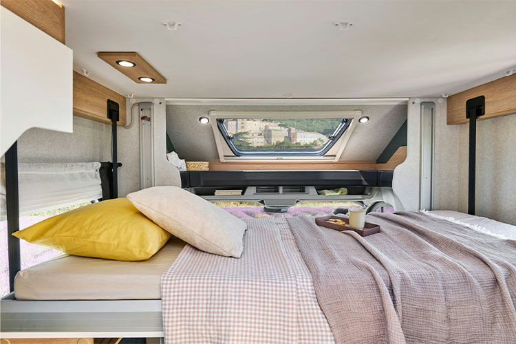 Cozy rv rental bedroom with a comfortable bed, pillows, and blankets, offering a scenic window view of distant buildings.. Pilote A630G 2025