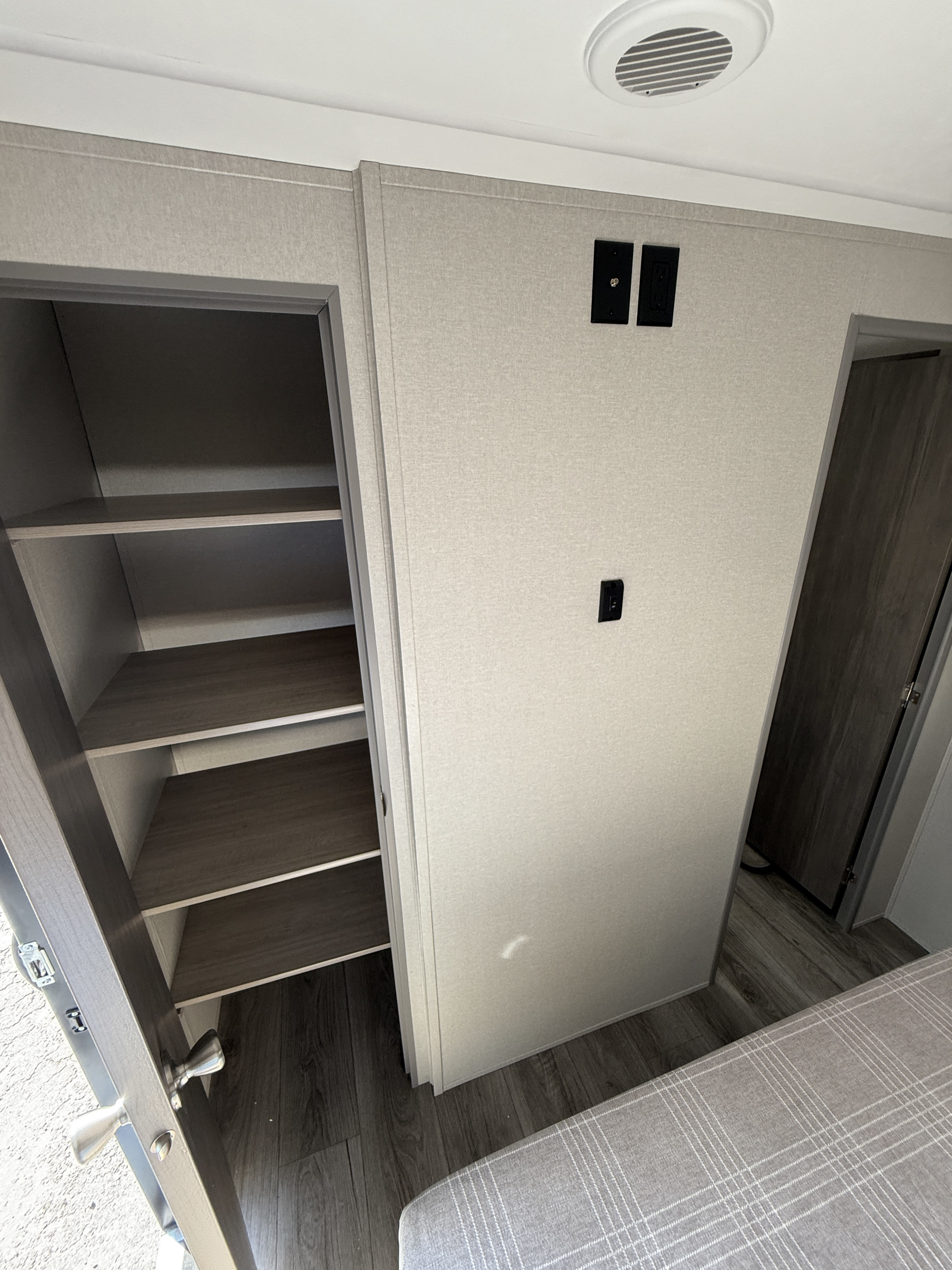 RV rental interior featuring a practical bedroom with an open closet, ample shelves, wall outlets, and a comfy bed.. Coachmen Catalina Legacy Edition 2025