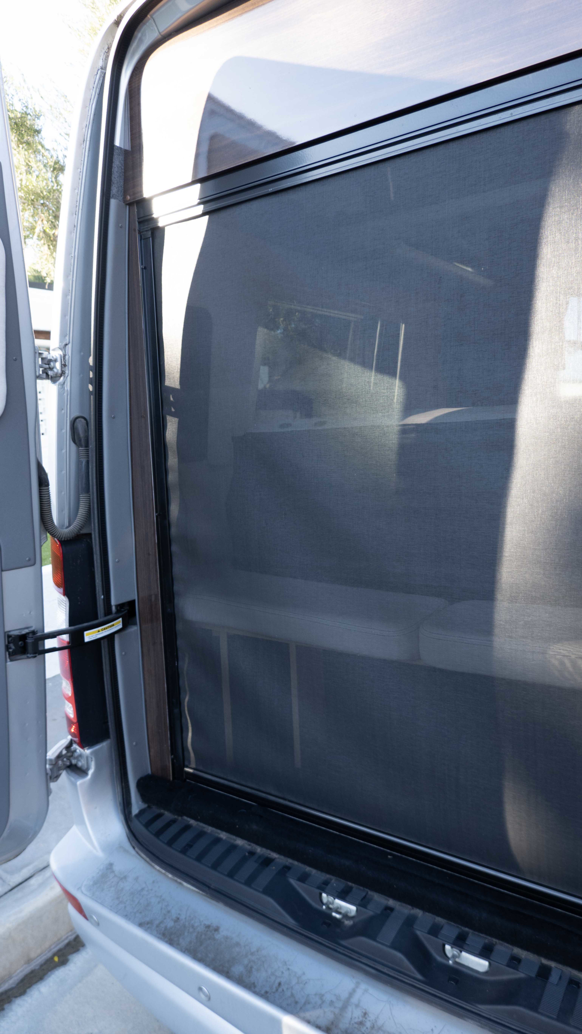 Rear screen door of an rv rental van, offering ventilation while showing glimpses of the interior seating.. Airstream Interstate 2015