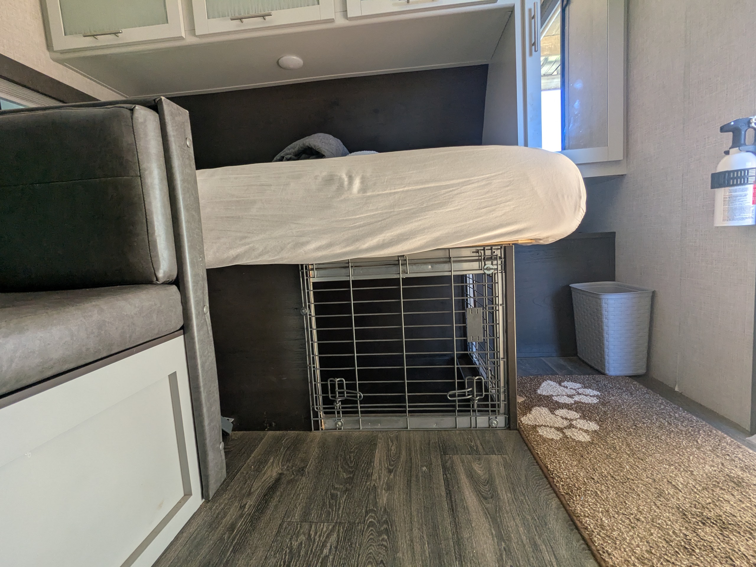 This RV rental interior showcases a clever space-saving design: an elevated bed with a dog crate fitting neatly underneath.. Keystone RV Bullet Crossfire 2021
