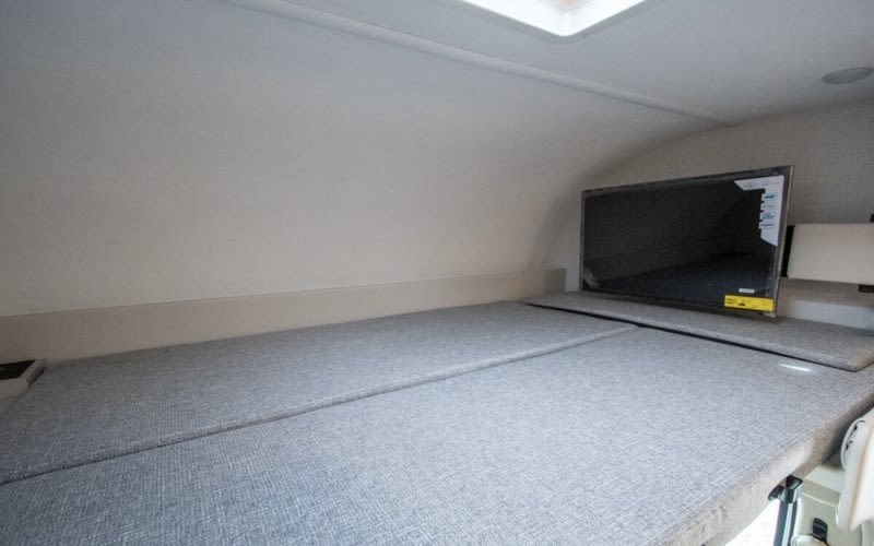 This rv rental offers a comfortable grey cushioned bed and a flat-screen TV, creating a cozy sleeping space.. Four Winds 22Z 2026