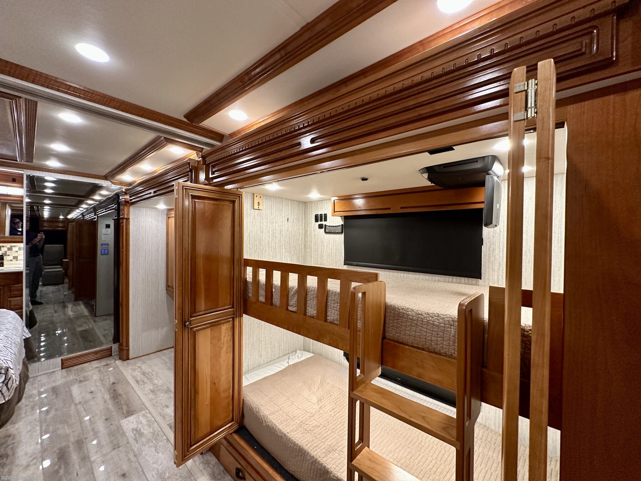 Inside an RV rental: wooden bunk beds, ornate ceiling trim, and a bright hallway reflected in a mirror on the left.. Newmar Dutch Star 2019