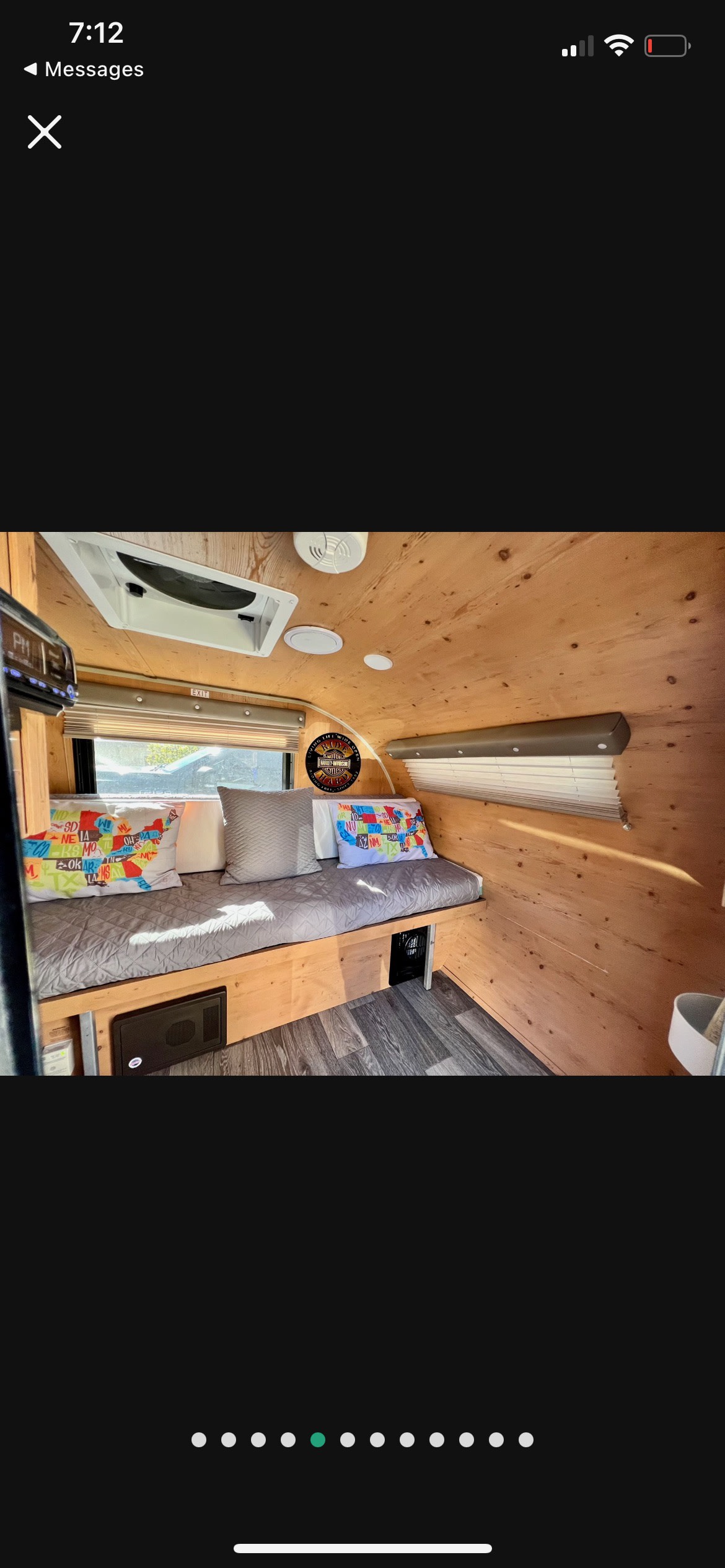 Cozy RV rental interior with wooden walls, a comfortable bed, map pillows, and dark flooring, ideal for travel.. Sunset Park RV Sun Lite 2018