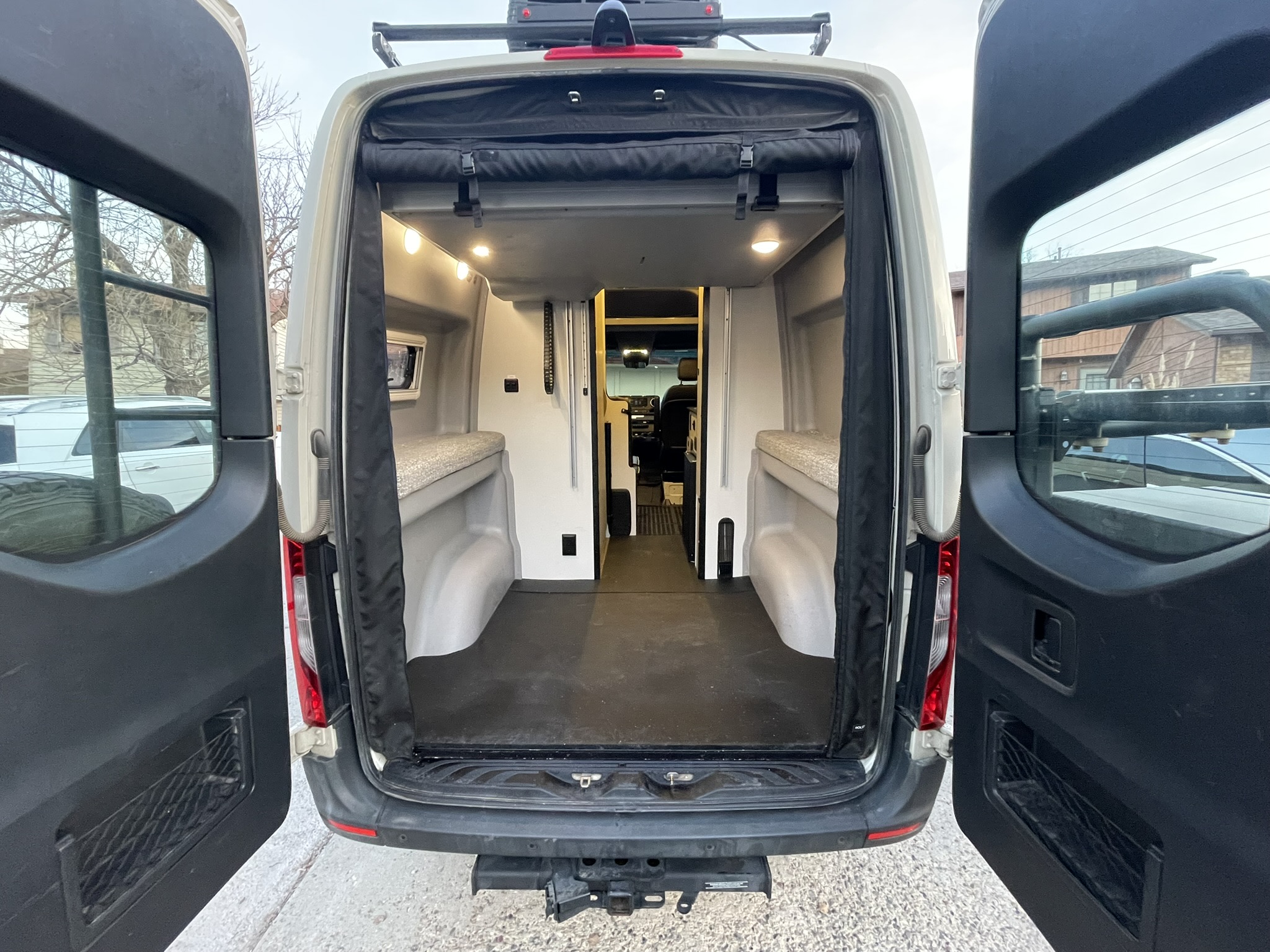 Rear view of this custom rv rental camper van, doors open to reveal its organized interior with sleeping platforms and storage.. Winnebago Revel 2020