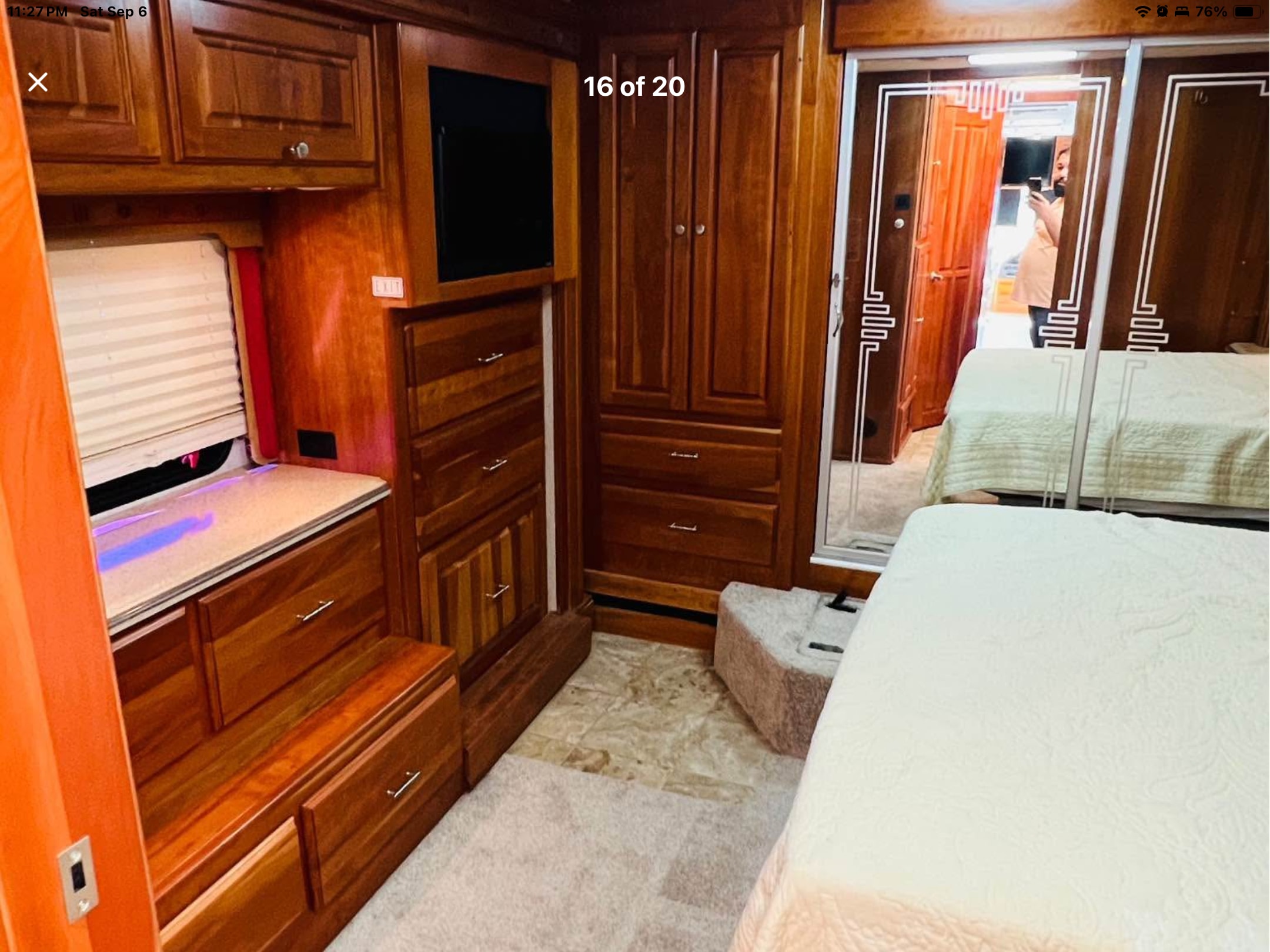 Spacious RV rental bedroom with warm wooden cabinetry, TV, and a cozy bed. Mirrored doors reflect the interior, offering a comfortable stay.. Holiday Rambler Scepter 2006