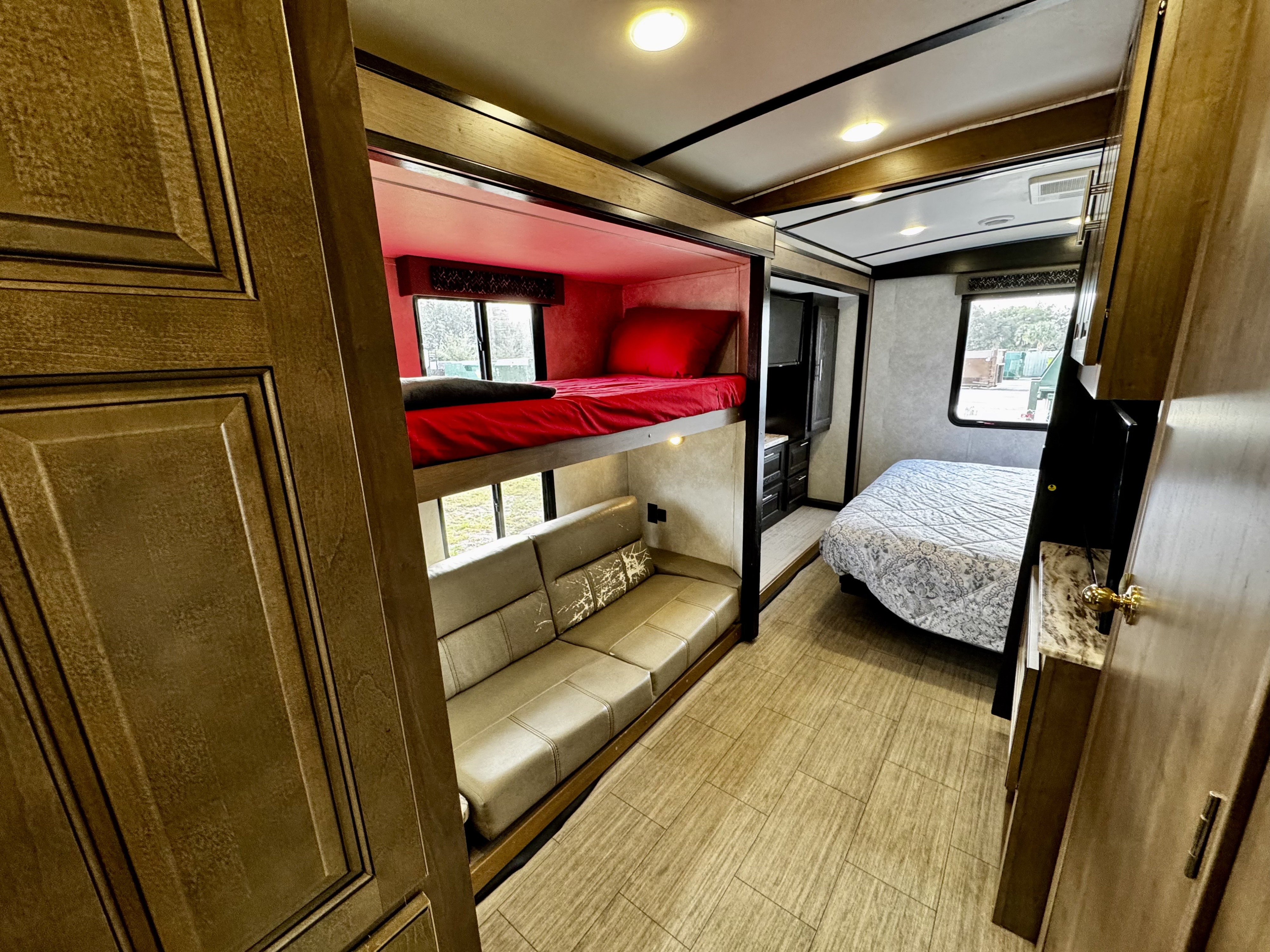 Cozy RV rental interior featuring bunk beds, a sofa, and a comfortable master bedroom area, ideal for family trips.. Forest River FR3 2021