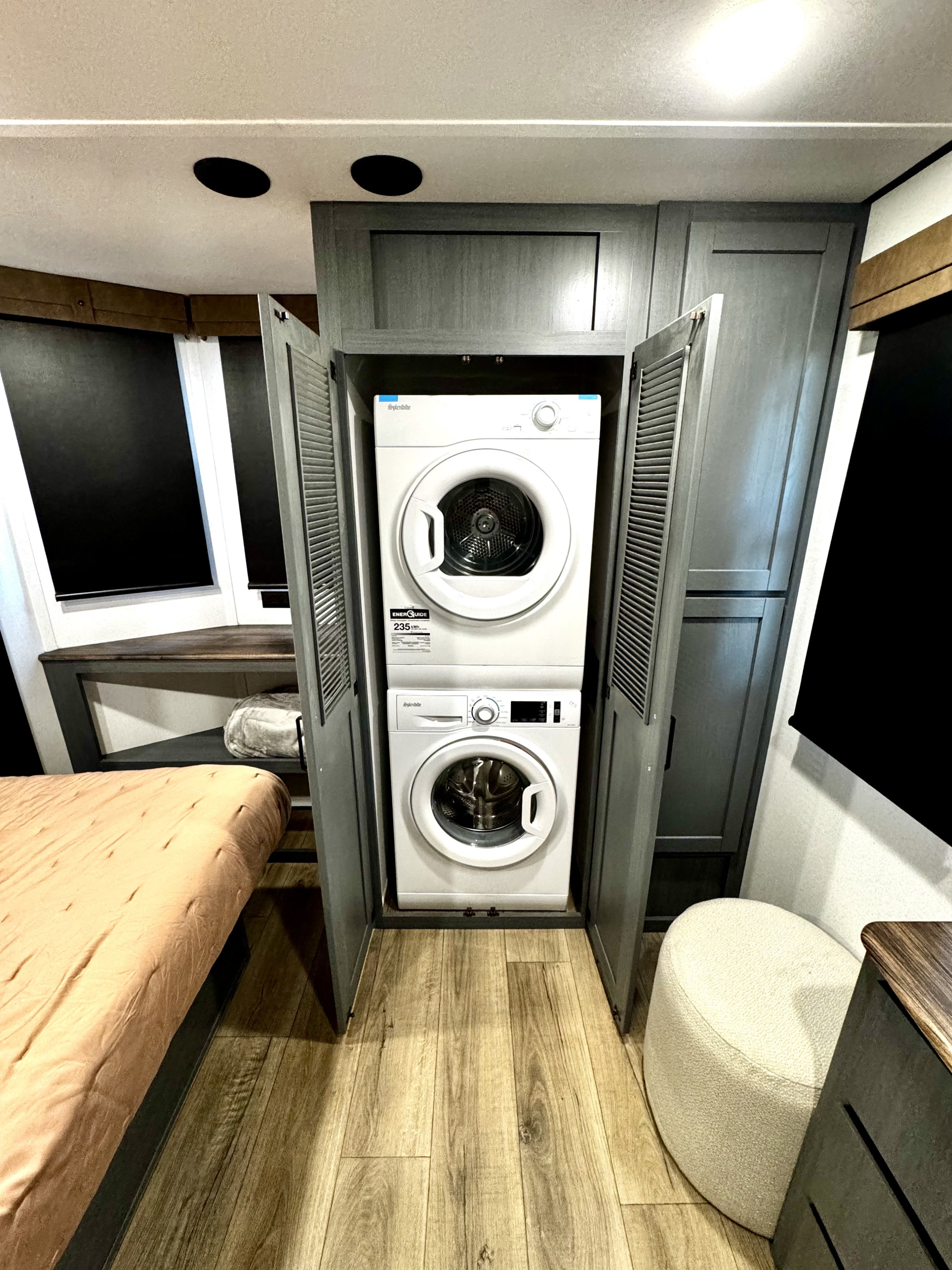 This RV rental features a convenient stackable washer and dryer unit built into a cabinet, offering laundry access in a compact bedroom setting.. Forest River Puma Destination 2025