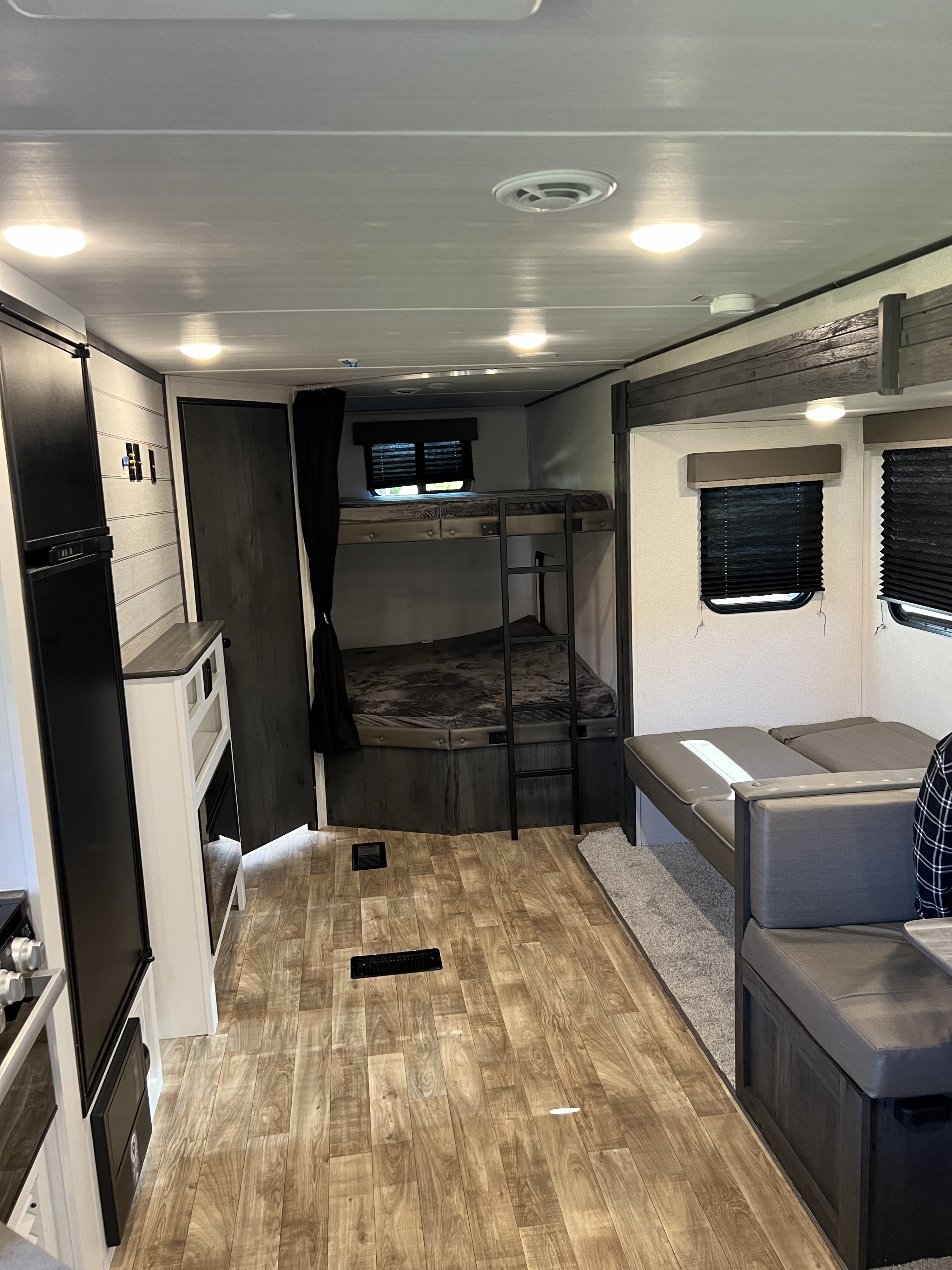Inside this spacious RV rental: a modern interior with bunk beds, a comfy dinette, and wood-look flooring. Ready for travel!. Keystone RV Hideout 2023