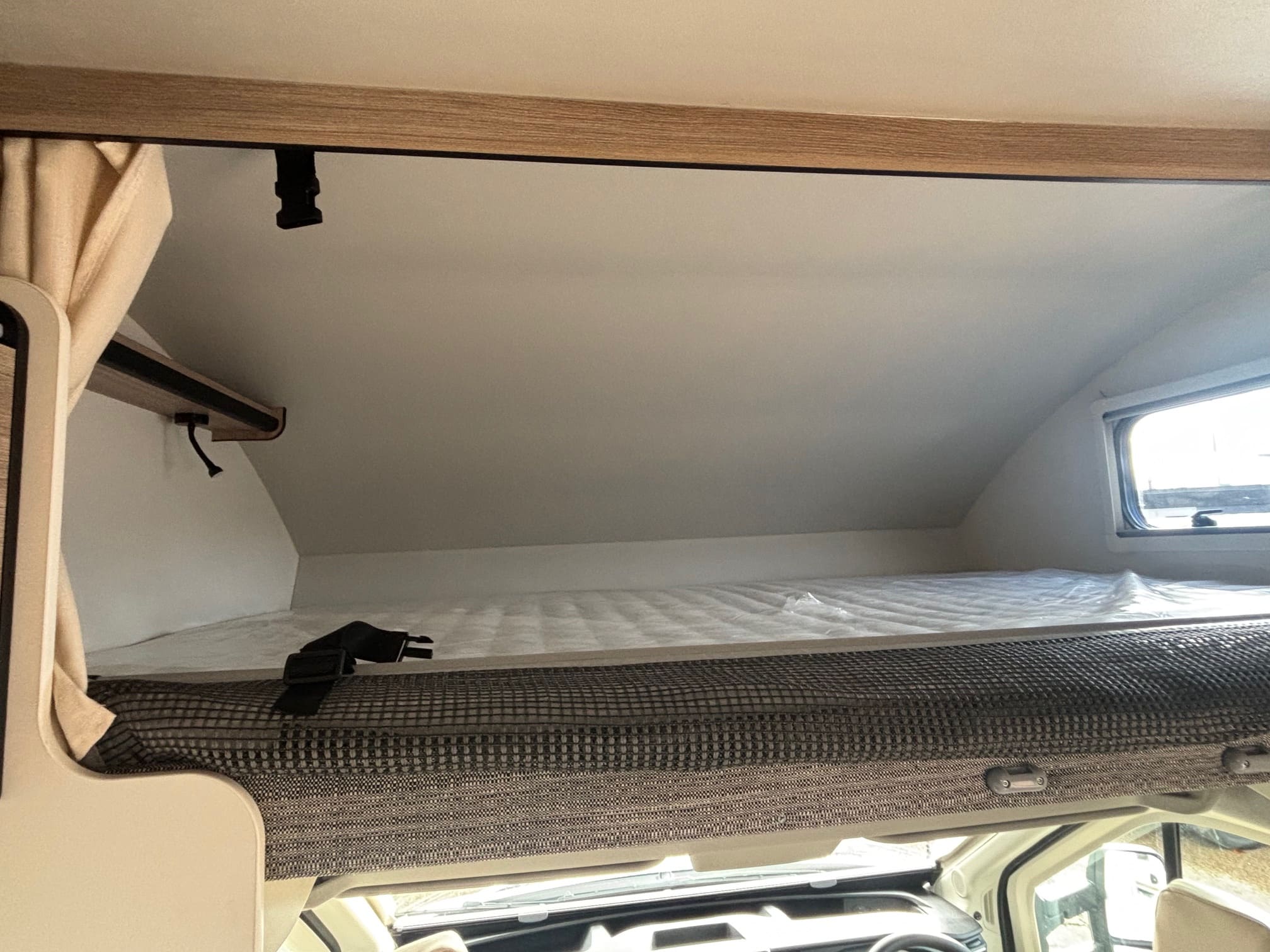 Cozy RV rental cab-over bunk with mattress, safety net, and window, ready for a comfortable night's sleep.. FORD TRANSIT RIMOR KILIG 669 5 BERTH 2026