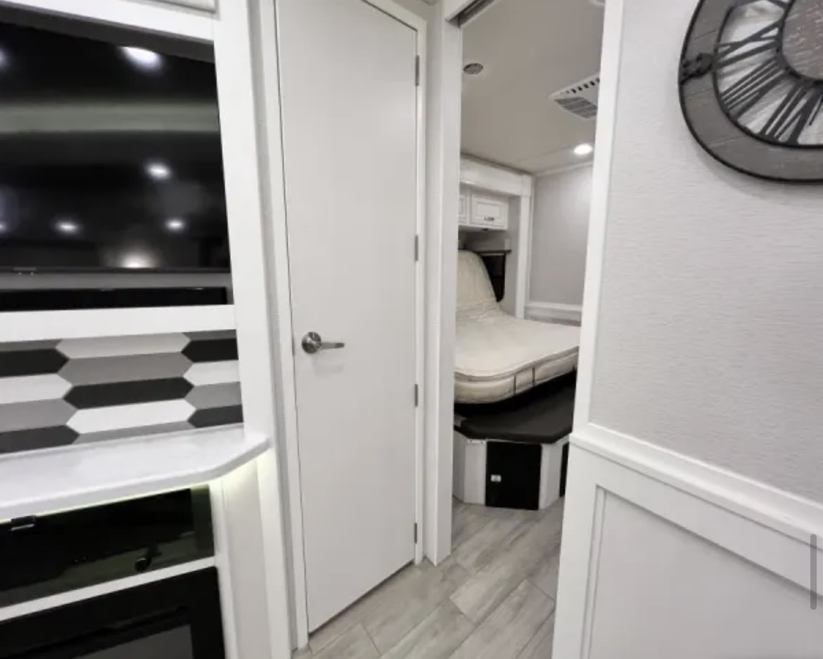 This RV rental offers a glimpse into its modern interior: a compact bedroom and a sleek entertainment setup.. Entegra Coach Accolade XL 2023