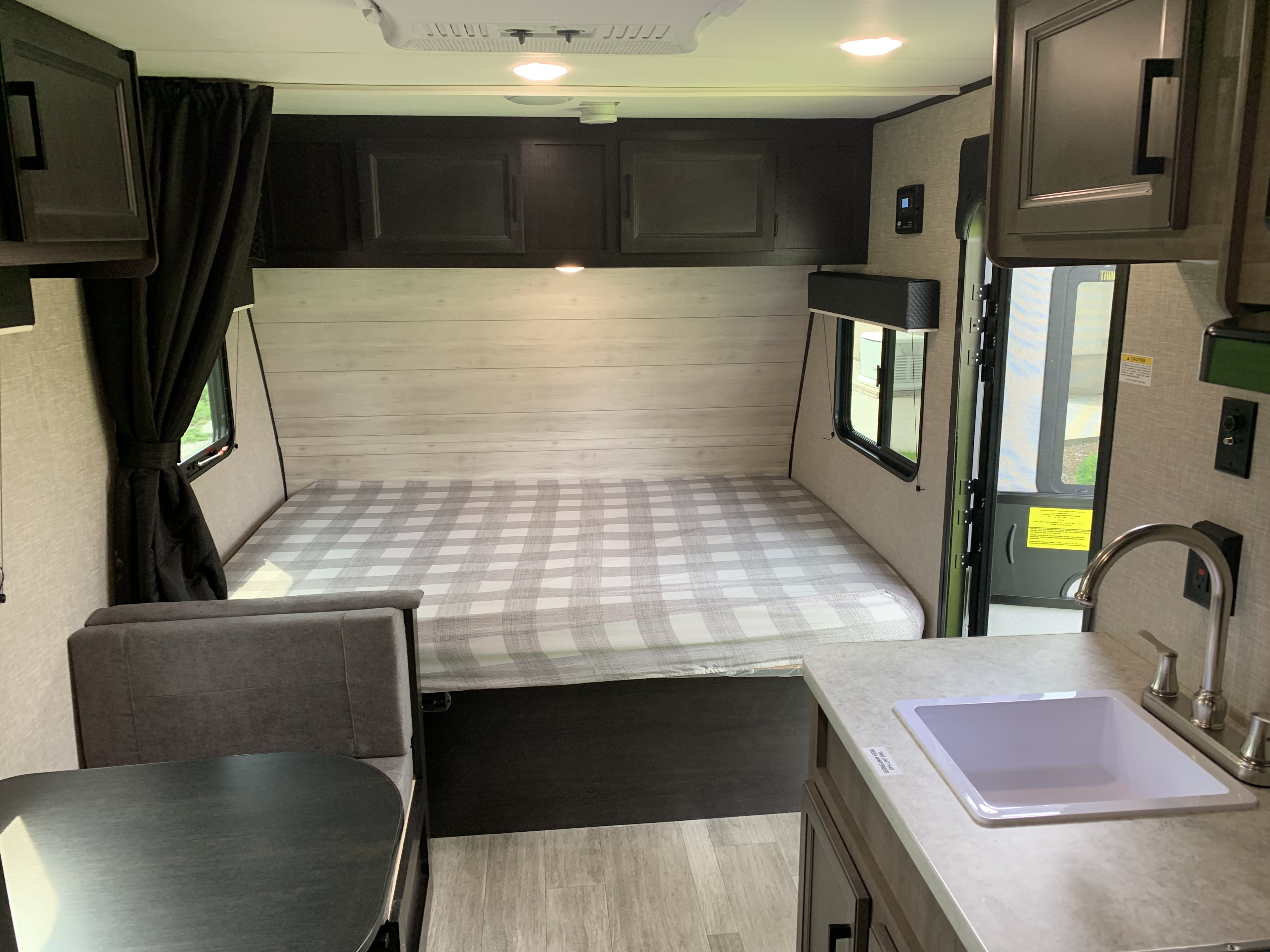 Cozy RV rental interior with a comfy plaid bed, compact dinette, kitchen sink, and ample overhead storage.. Jayco Jay Flight SLX STX Edition 2022