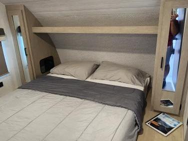 Cozy RV rental bedroom featuring a comfortable queen bed with shelf & storage. Perfect for your next travel adventure.. Forest River Salem 2024