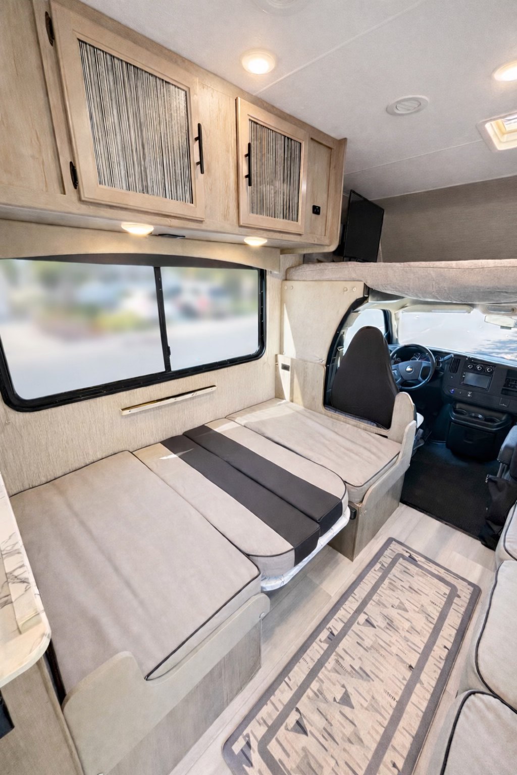 Spacious RV rental interior with a convertible dinette/bed, overhead cabinets, and front bunk. Ideal for comfortable travel.. Forest River Coachmen Freelander 2022