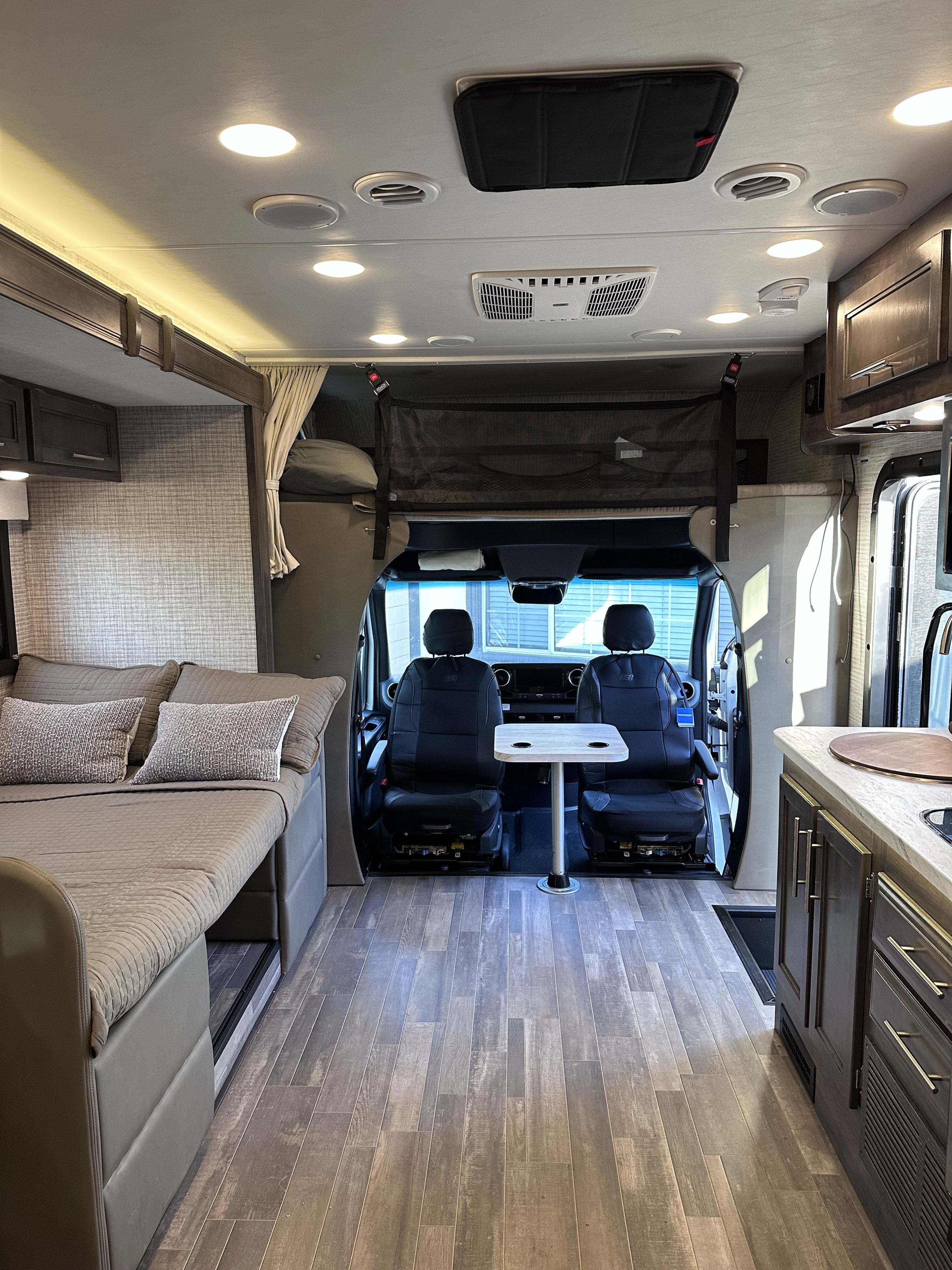 Inside a modern rv rental, featuring a comfortable bed, compact kitchen, and front swivel seats, ready for adventure.. Entegra Coach Qwest SE 2025