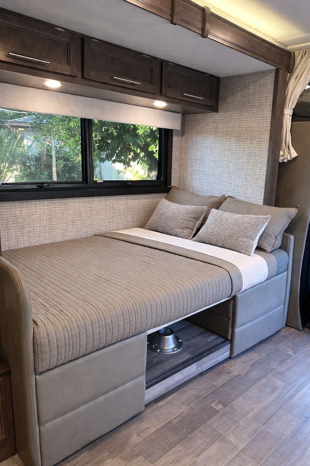 Comfortable, convertible bed in this RV rental interior, featuring overhead cabinets and a large window.. Entegra Coach Qwest SE 2025