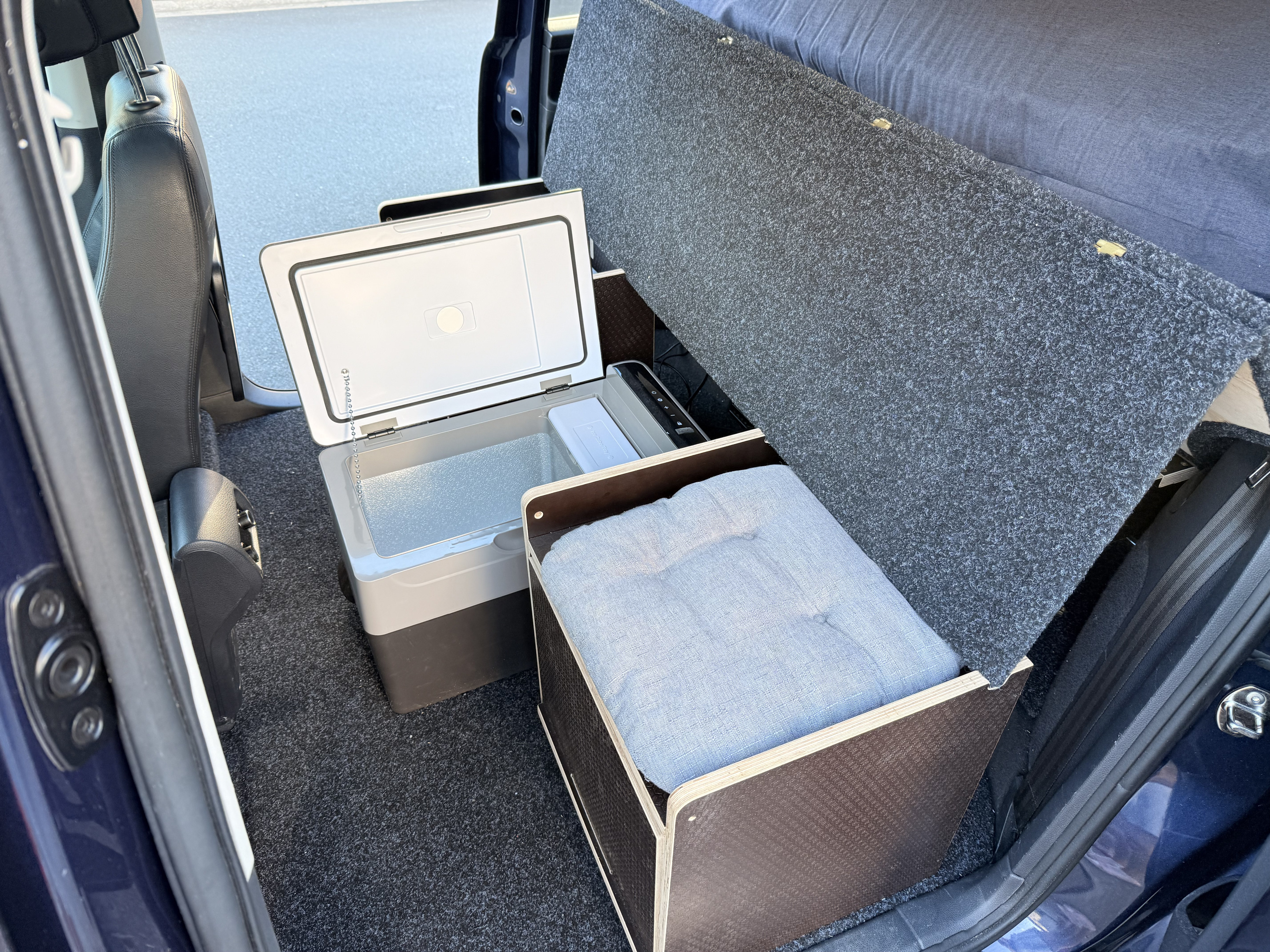 Compact rv rental interior with portable fridge, storage box, and convertible bed setup for road trips.. Volkswagen Sharan 2012