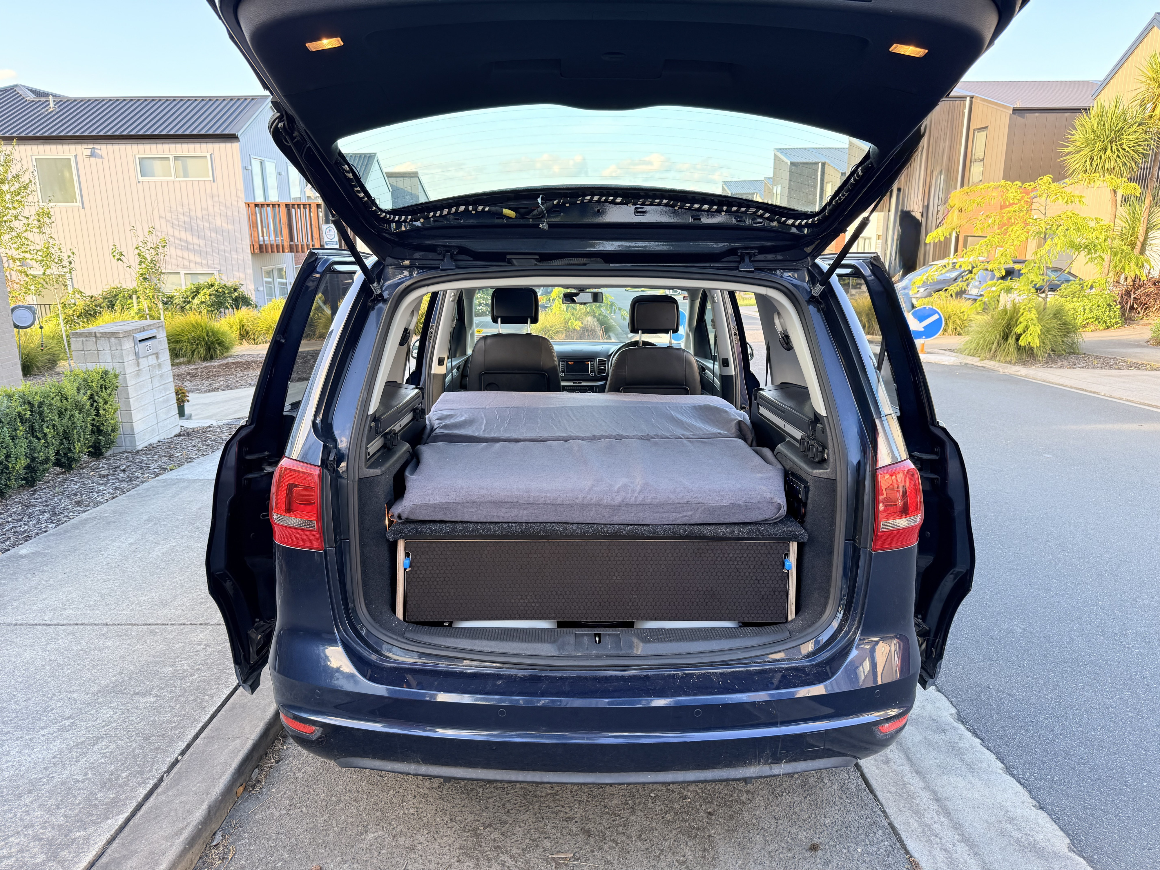 This RV rental features a minivan converted into a compact camper with a custom bed setup for travel.. Volkswagen Sharan 2012