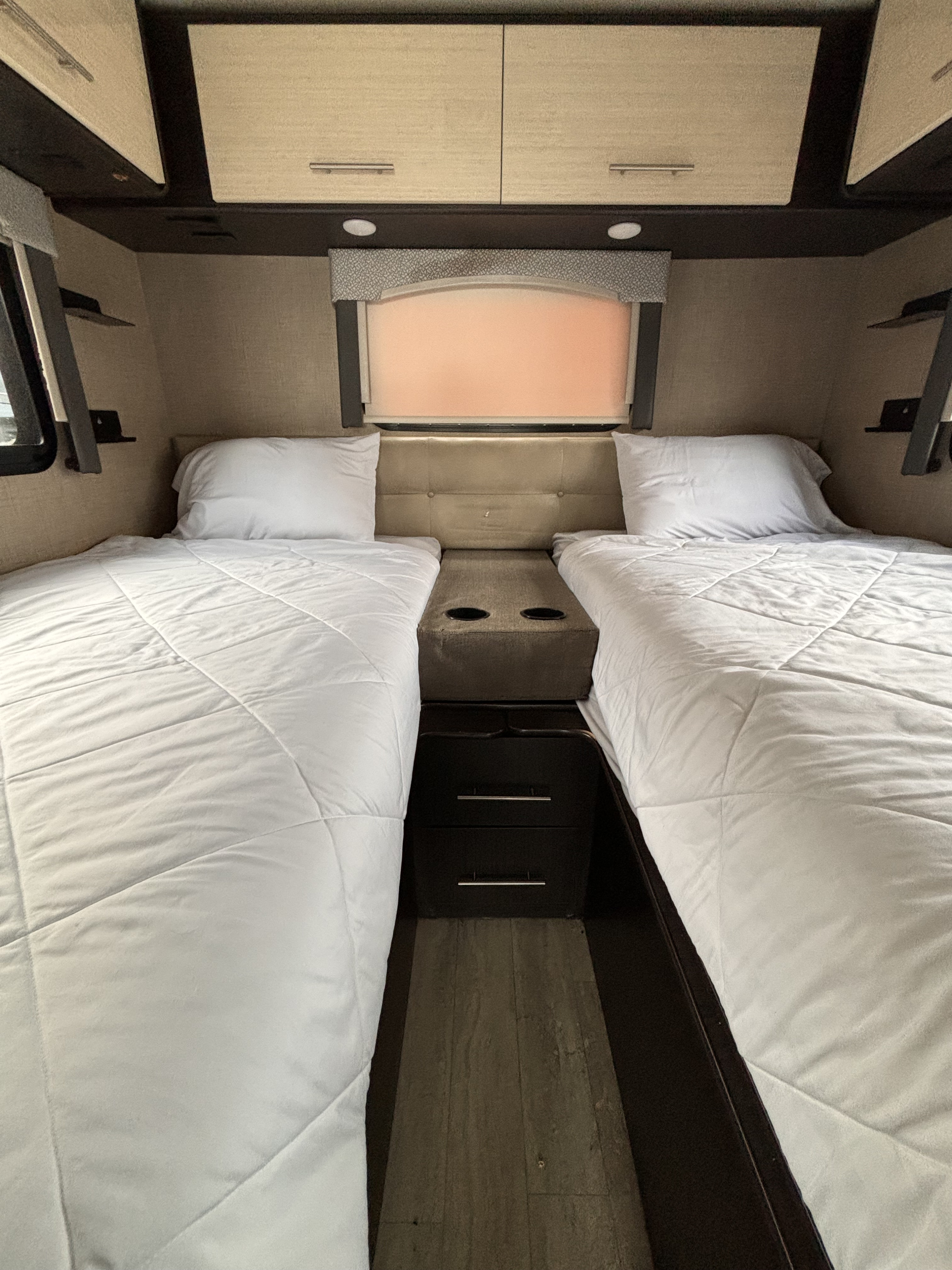 RV rental bedroom with two cozy twin beds, overhead storage, and a center console/nightstand. Ideal for travel.. Thor Vegas 2020