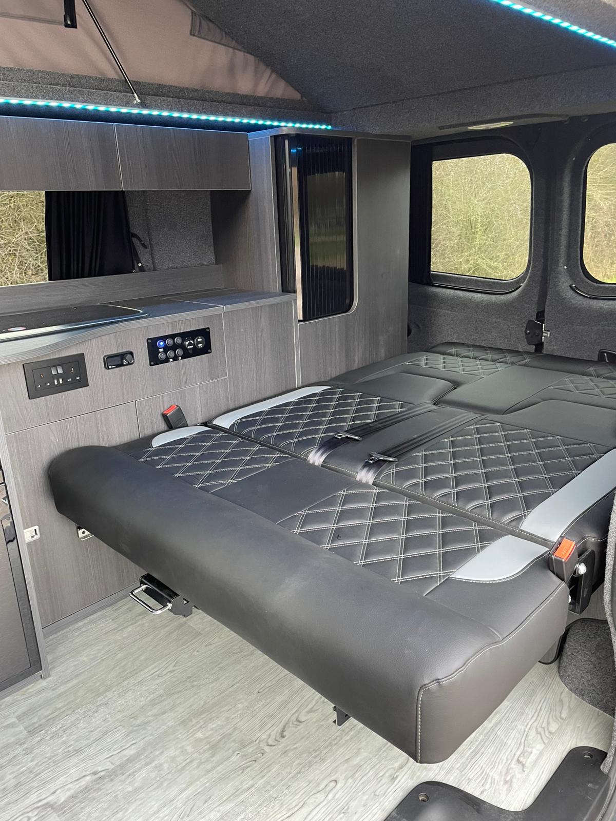 Stylish rv rental interior: custom bed/seating with diamond stitching, compact kitchen, fridge, and ambient LED lighting.. Renault Traffic 2020