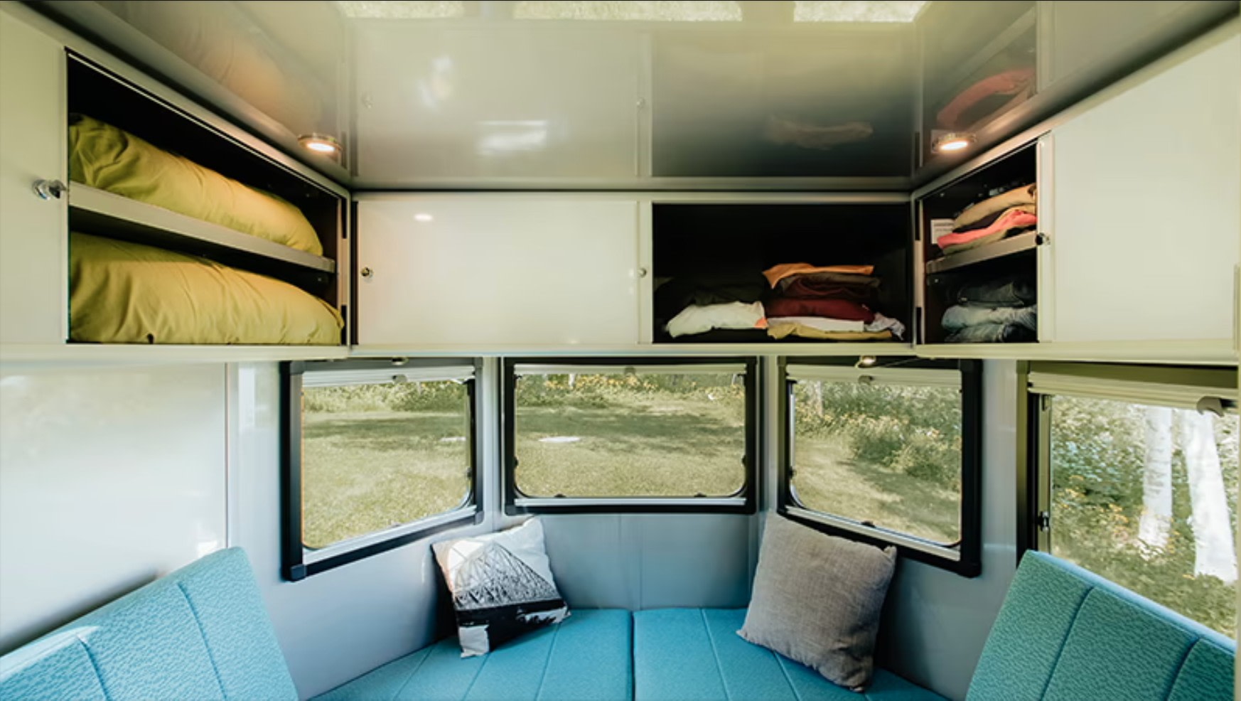 Cozy RV rental interior: organized overhead storage for bedding & clothes, comfy bench seating, and scenic windows.. Safari Condo A2124 2025