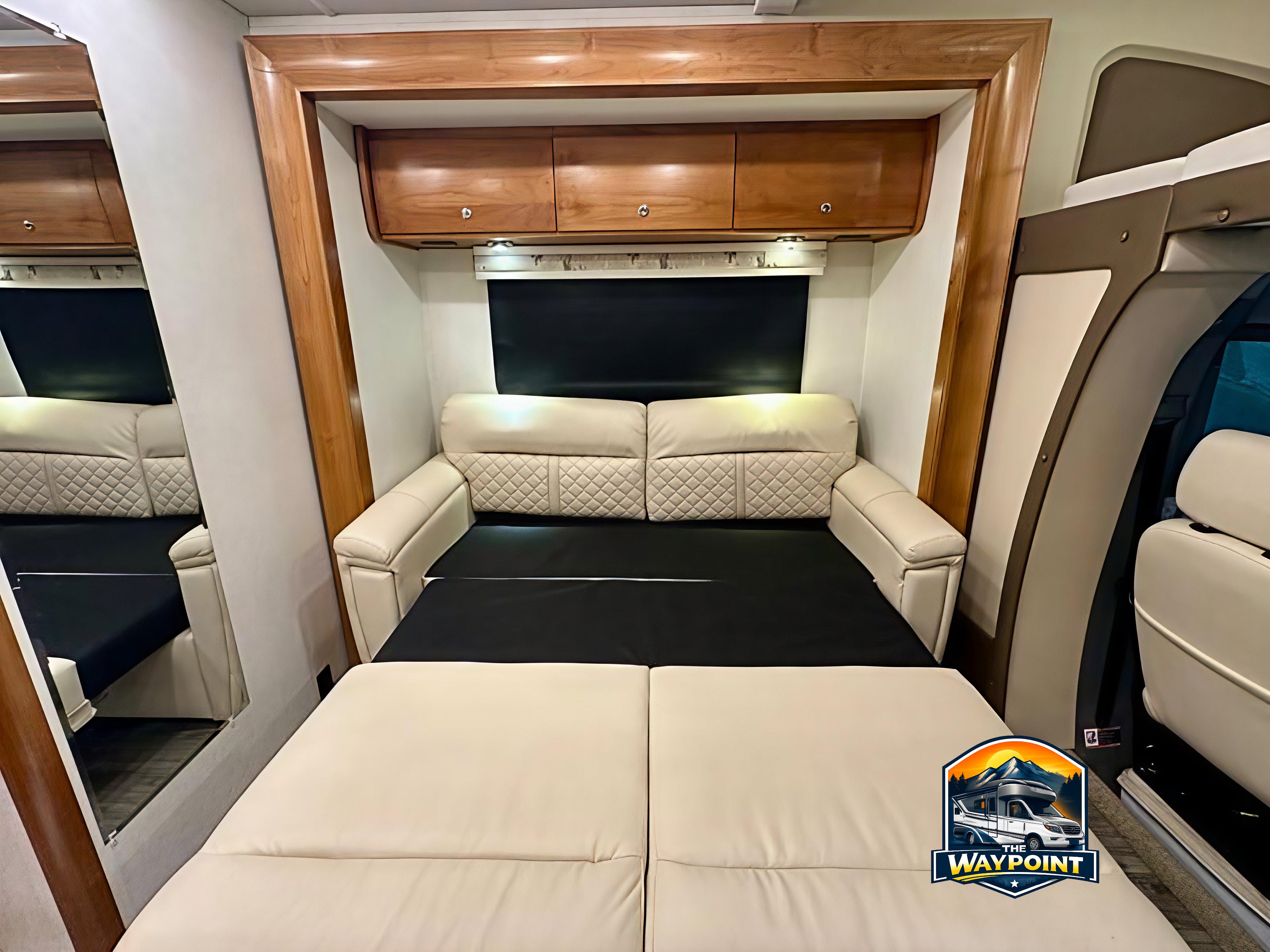 Comfortable cream sofa converts to a bed in this RV rental interior, featuring wood cabinets and cozy lighting.. Wayfarer Wayfarer Motorhome 2019
