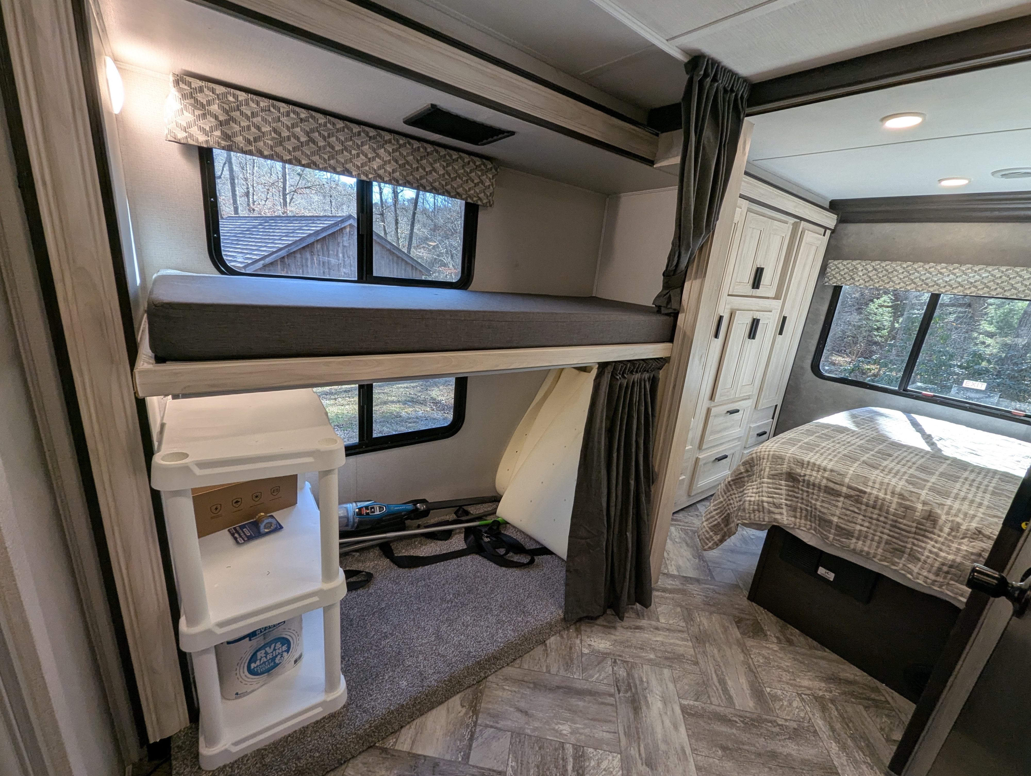 This RV rental interior features stacked bunk beds, a main bed, and light-toned storage cabinets, offering comfort for your journey.. Forest River Forester 2023