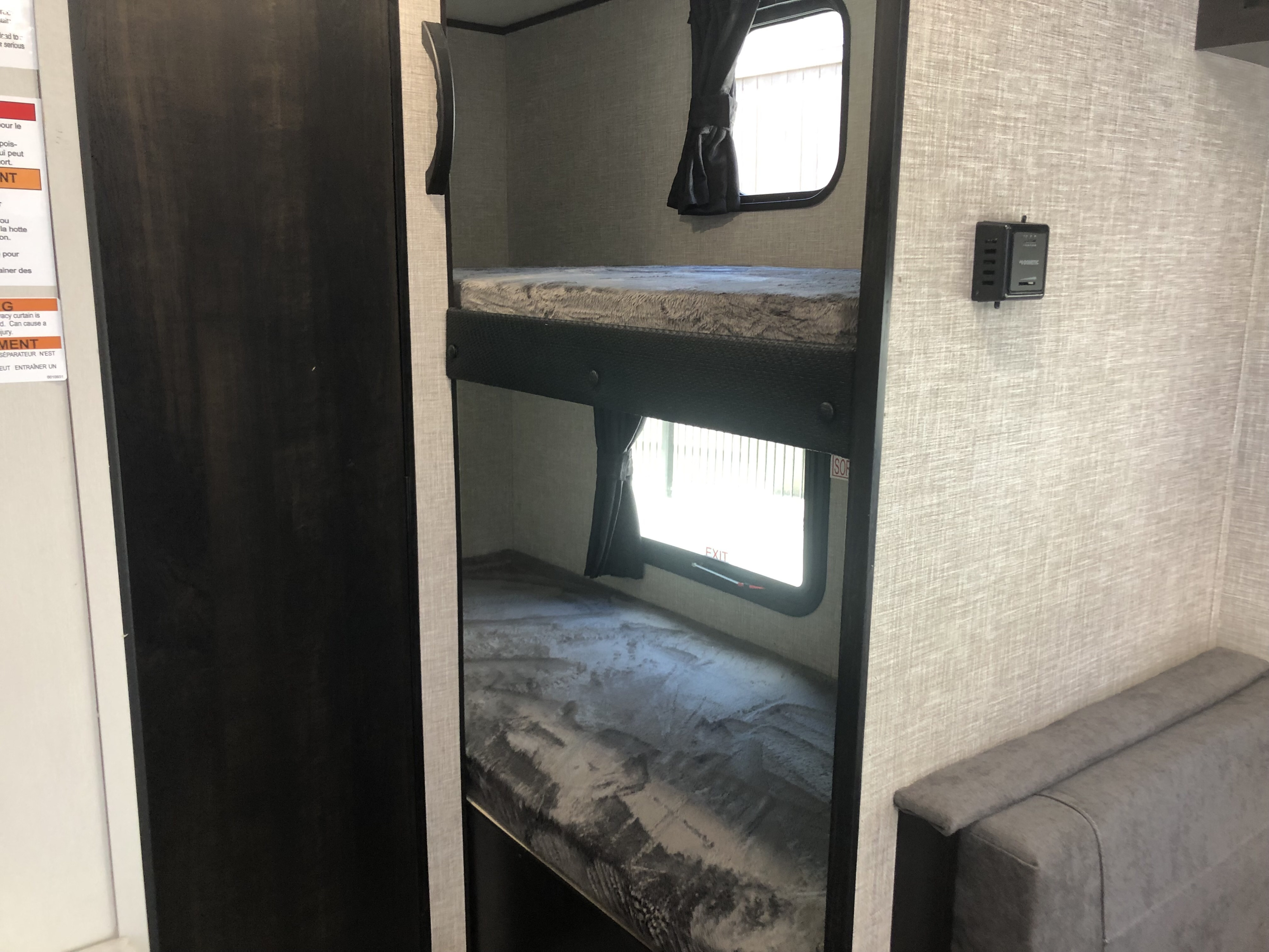 RV rental interior featuring cozy bunk beds with windows, privacy curtains, and an exit sign for safety.. Jayco Jay Flight SLX 2022