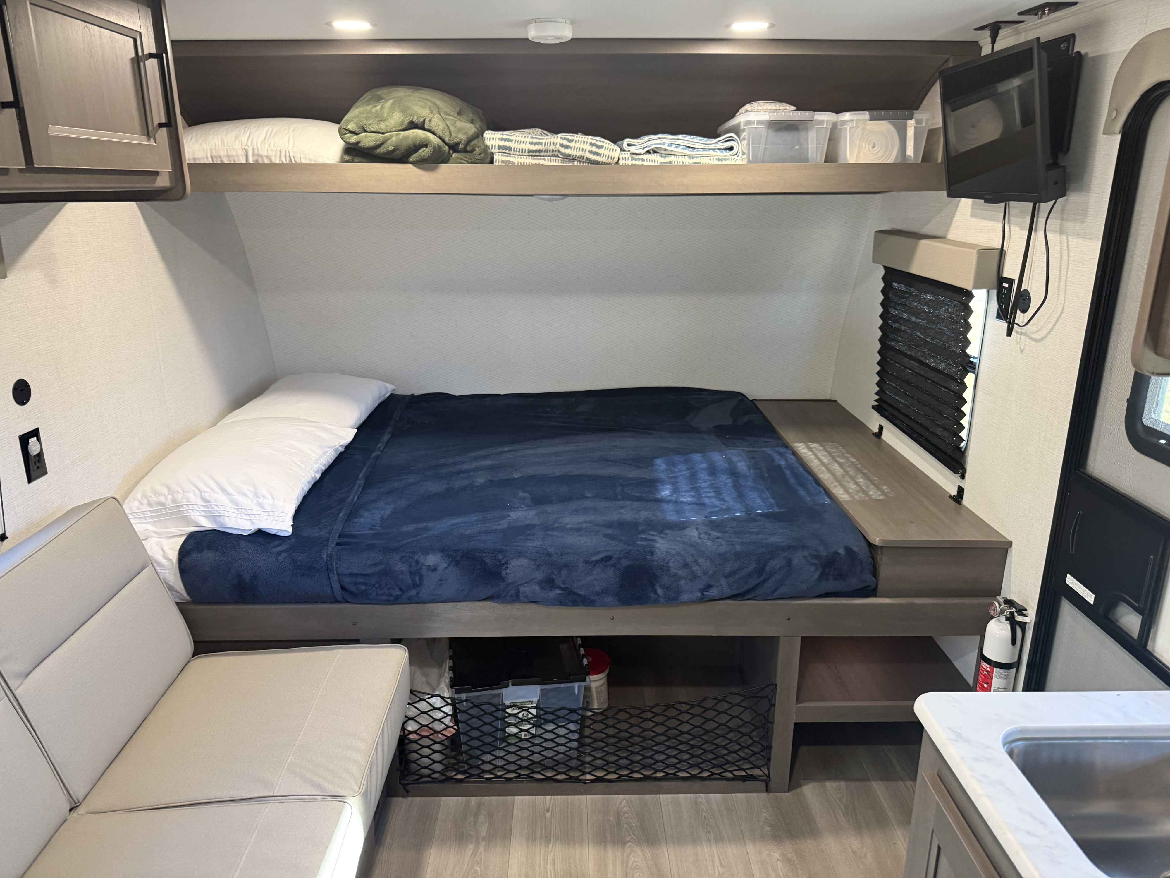 Cozy RV rental interior: bed with storage, sofa, and overhead cabinets for a comfortable stay.. Grand Design Transcend One 2025