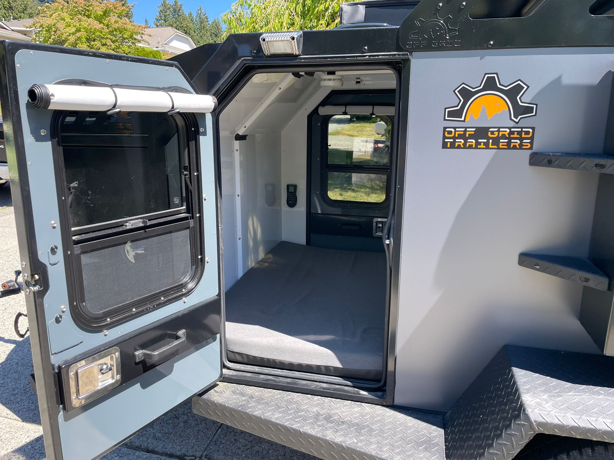 Inside an Off Grid Trailers RV rental: compact, rugged camper with open door showing bed & controls, ready for adventure.. Off Grid Trailers Off Grid Trailers Trailer 2021