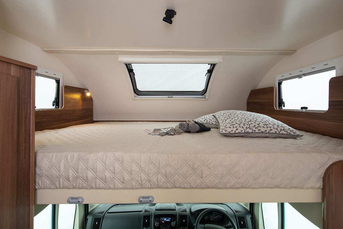 Cozy RV rental sleeping area with a large bed, side windows, and overhead vent, positioned above the driver's cab.. Auto Roller 746 Roller Team 746 2019