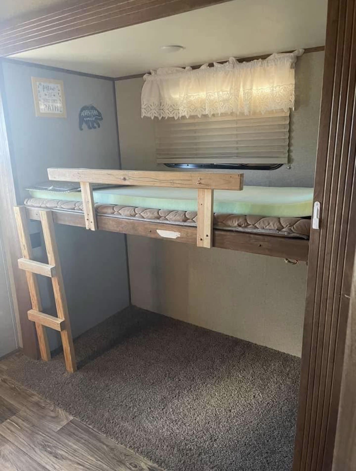 RV rental bunk bed with ladder, mattresses, window, and decor. A compact sleeping area for your travels.. Keystone RV Laredo 2019