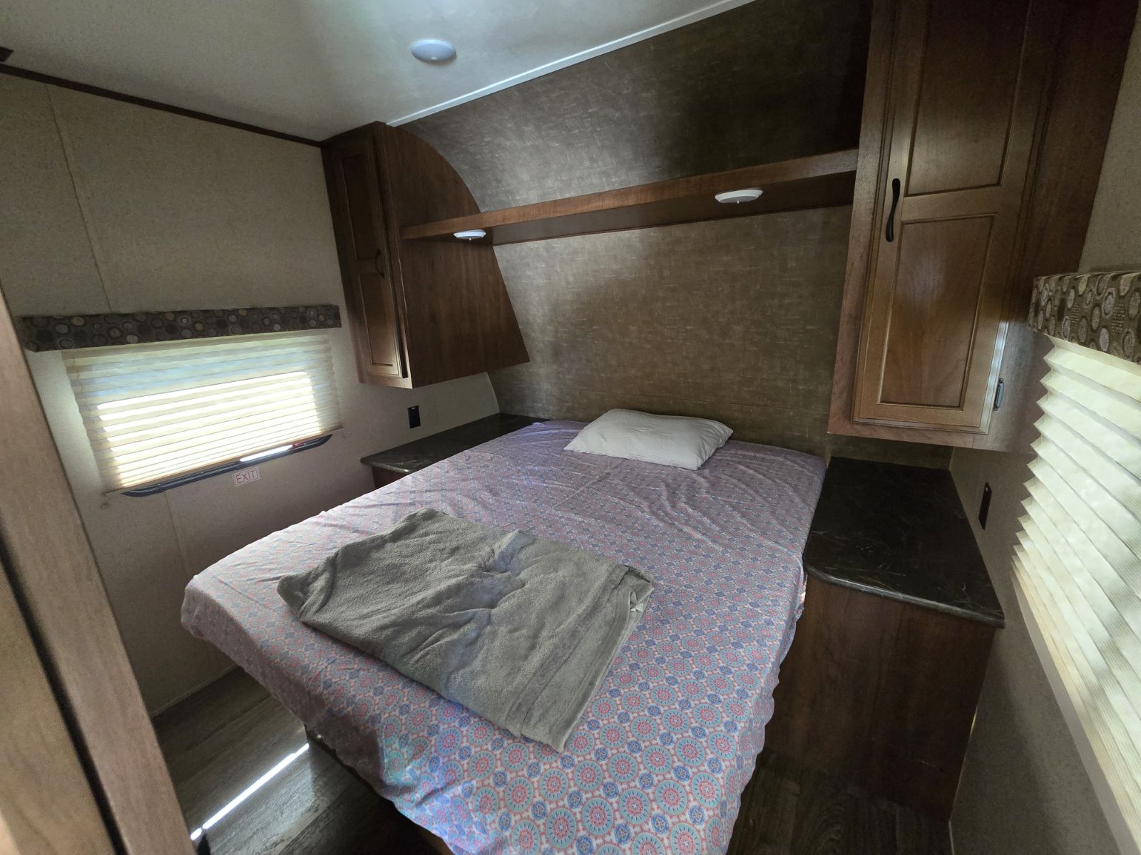 RV rental bedroom interior: bed with patterned cover, overhead cabinets, and window. Ready for your next travel adventure.. Jay Flight SLX 287BHSW 2016