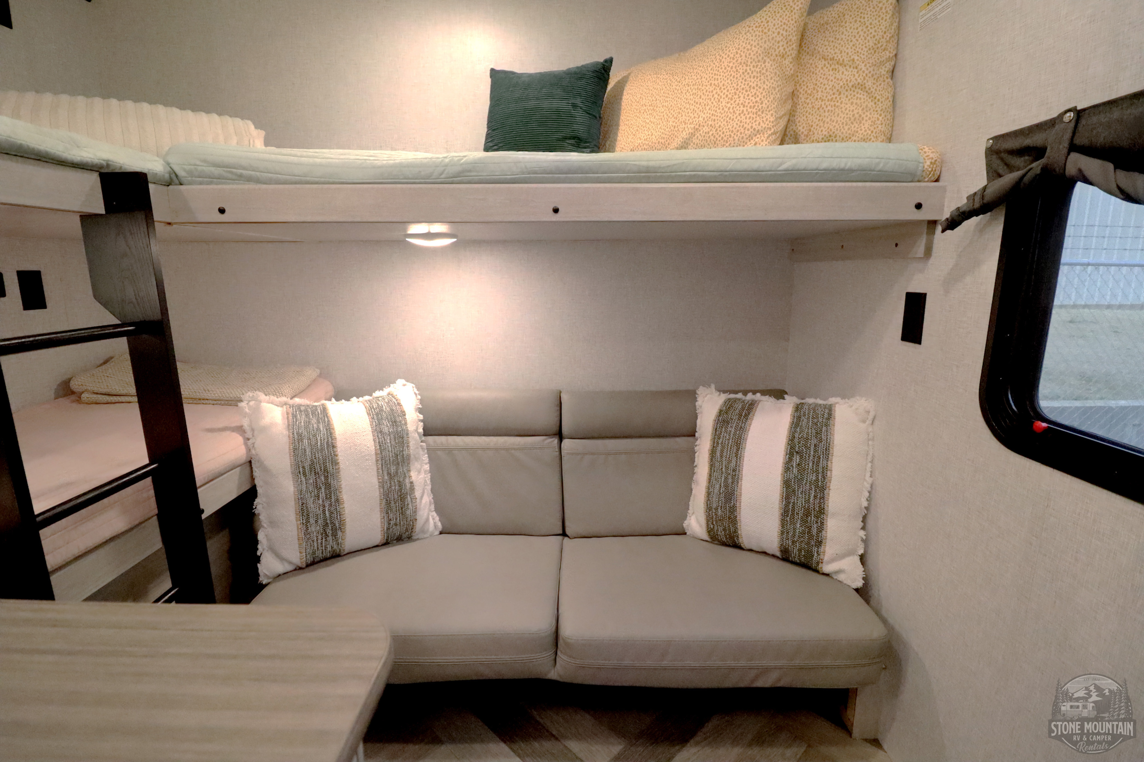 RV rental interior featuring bunk beds, a comfortable couch, and a small dining table. Ideal camper living space.. Crossroads RV Zinger 2024