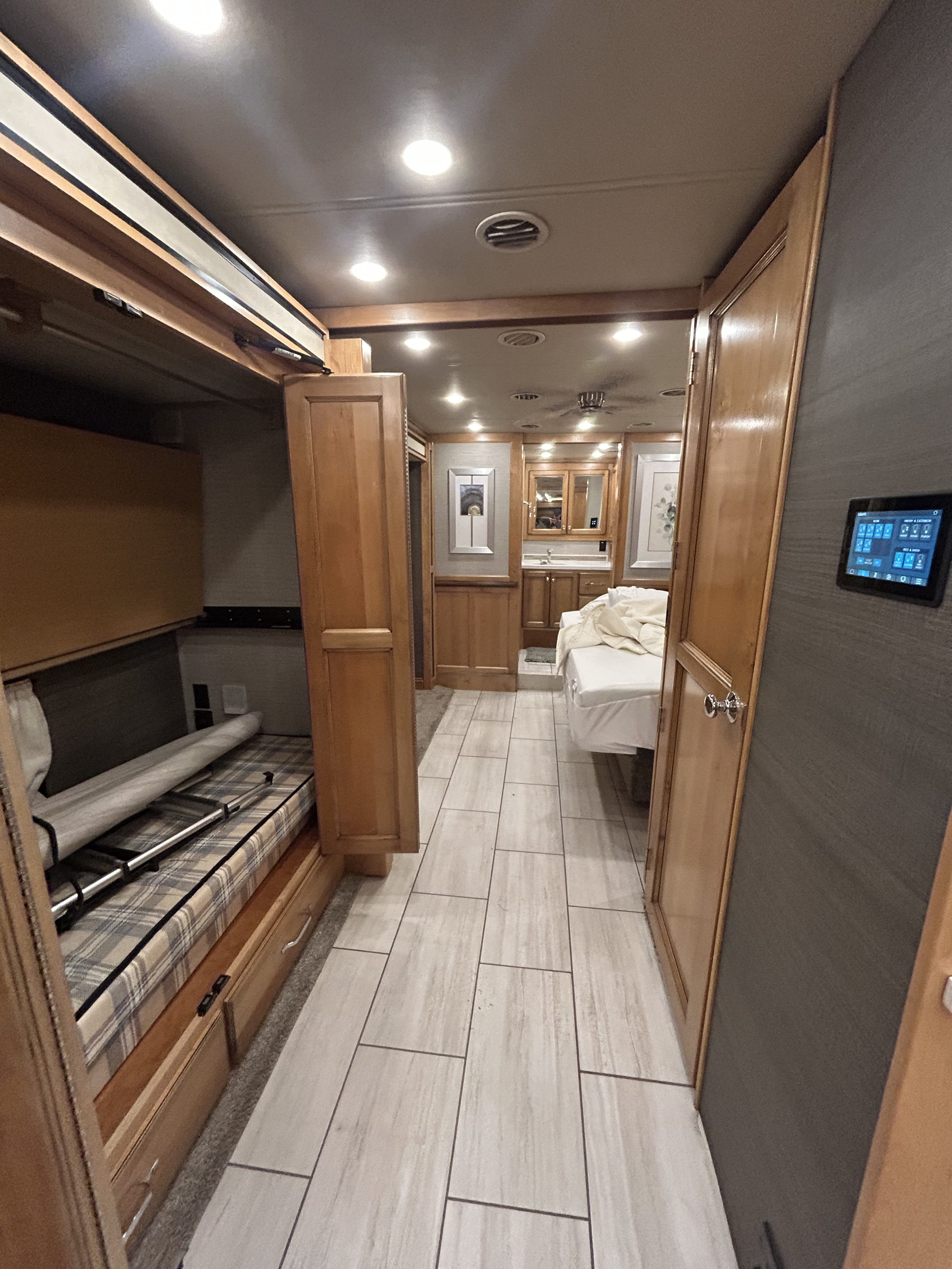 RV rental interior: Aisle leads past bunk beds on left, toward rear bedroom with bath, and digital controls on right.. Tiffin Allegro Red 2021
