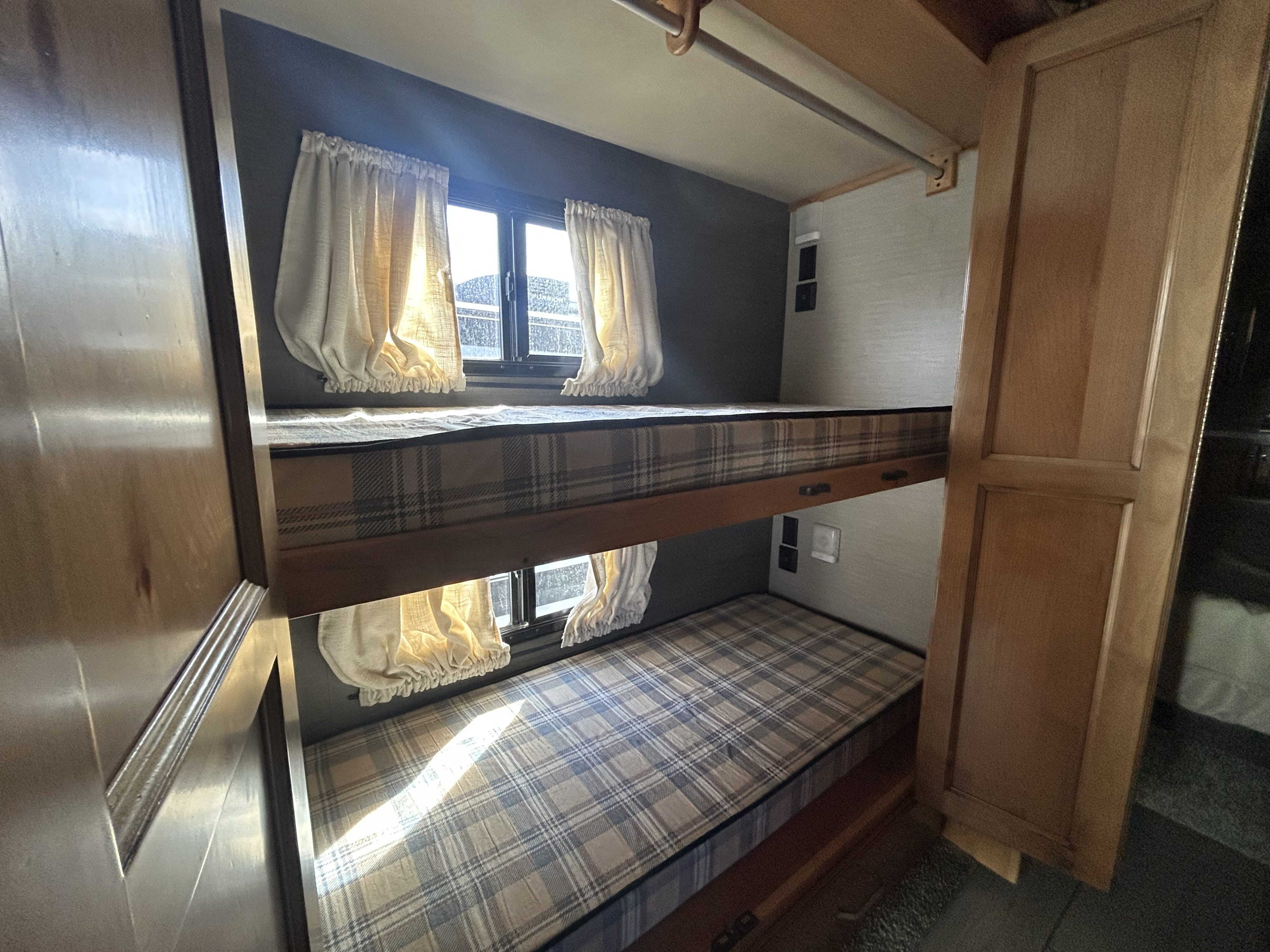 Cozy rv rental bunk beds with plaid mattresses and windows with curtains, offering a compact sleeping area.. Tiffin Allegro Red 2021