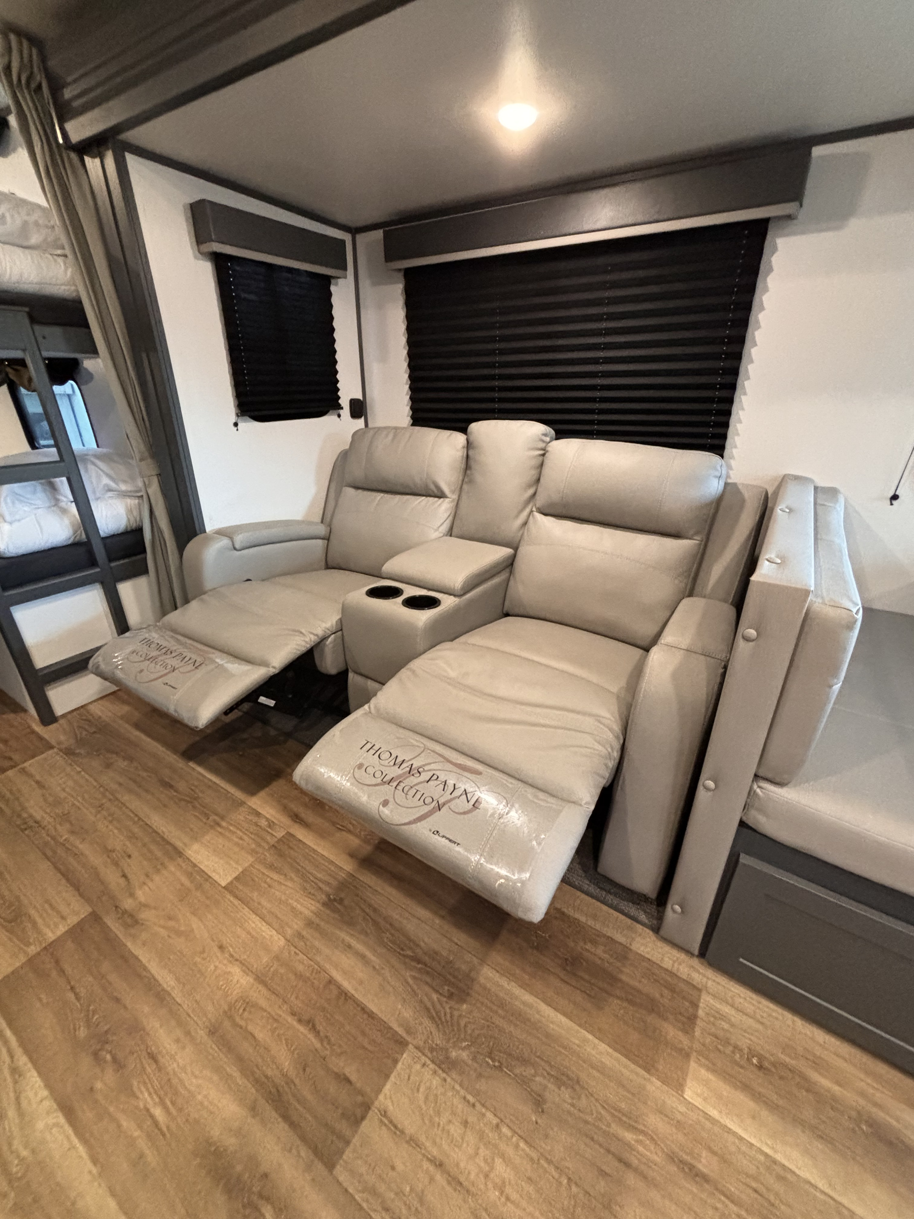 Comfortable RV rental interior featuring new Thomas Payne recliners with cup holders, bunk beds, and wood-look flooring.. Keystone RV Bullet 2022