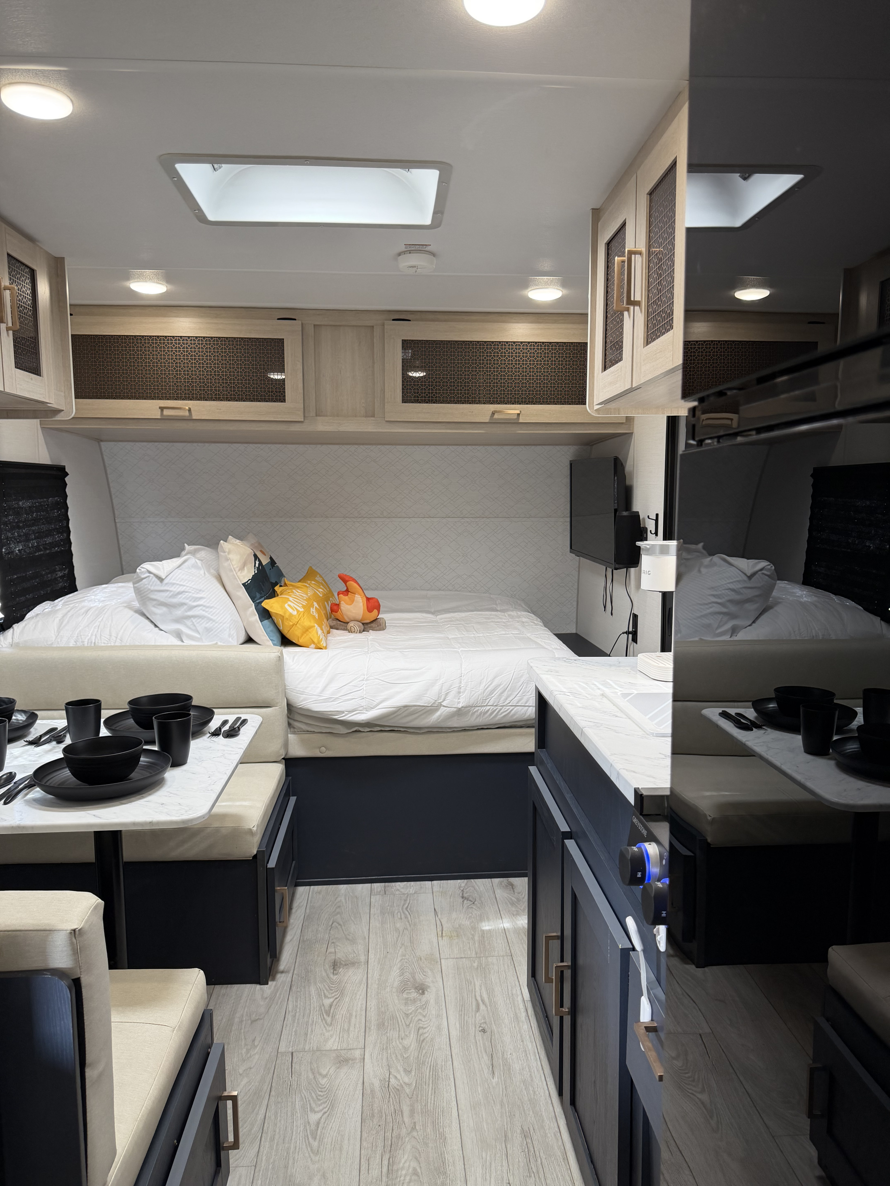 Cozy RV rental interior: bed with plush pillows, dining table set, and sleek kitchen counter. Modern and inviting.. Forest River Primetime Avenger 2025