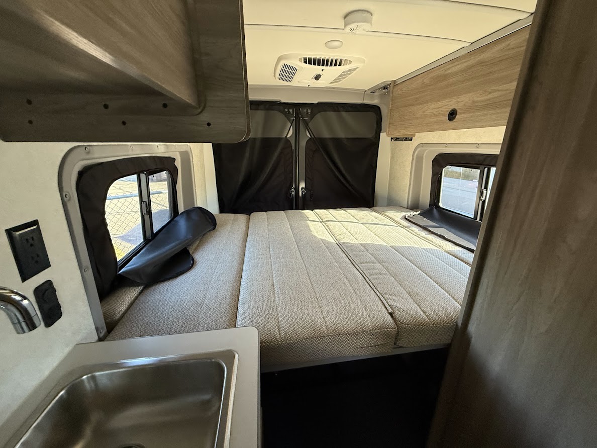 RV rental interior: a comfy bed, small sink, and windows with blackout shades offer a compact travel space.. Winnebago Solis 59PX 2026