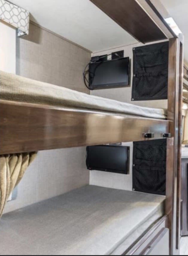 Enjoy comfort in this RV rental with cozy bunk beds, each featuring a personal TV and mesh storage for essentials.. Thor Quantum SE 2020