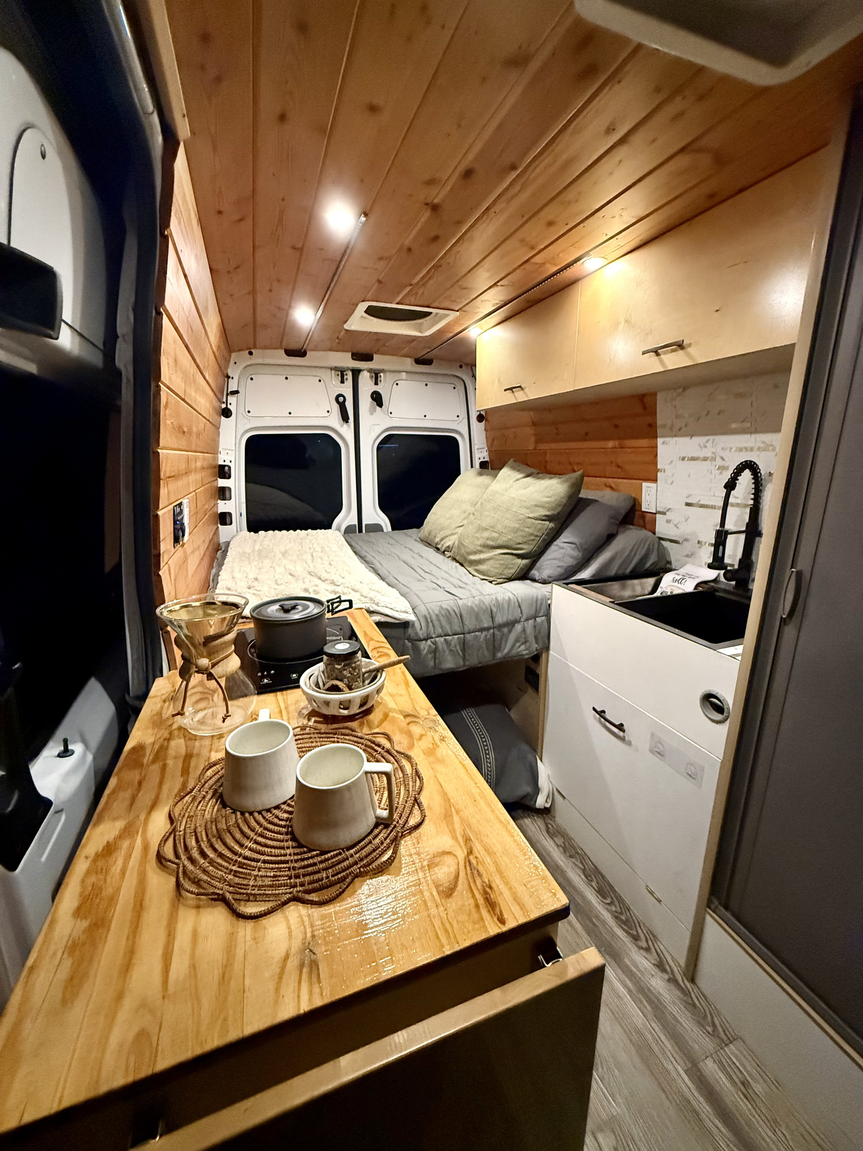 Cozy RV rental interior with wooden walls & ceiling, bed, kitchenette, and coffee station. Perfect for travel!. Mercedes-Benz Sprinter 2500 2014