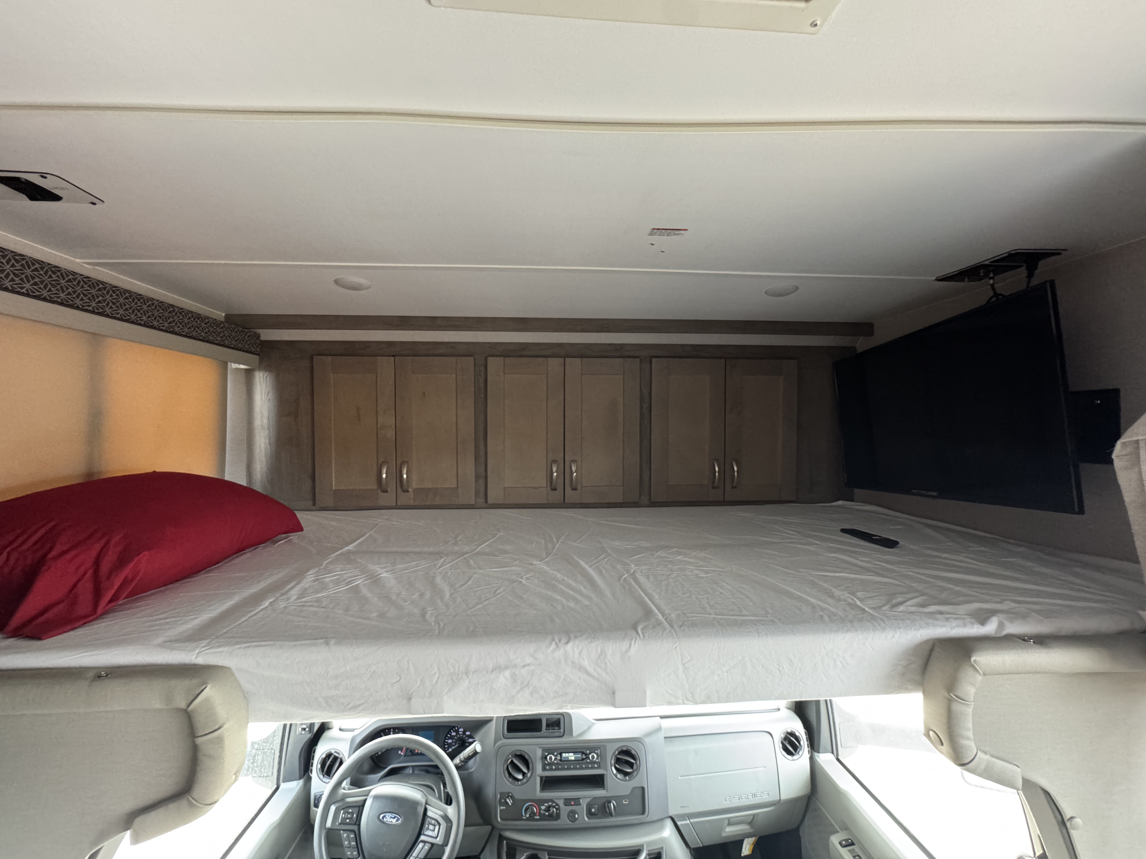 Interior view of an rv rental showing the overhead bunk bed, cabinets, TV, and driver's cockpit below.. Gulf Stream 63111 2024